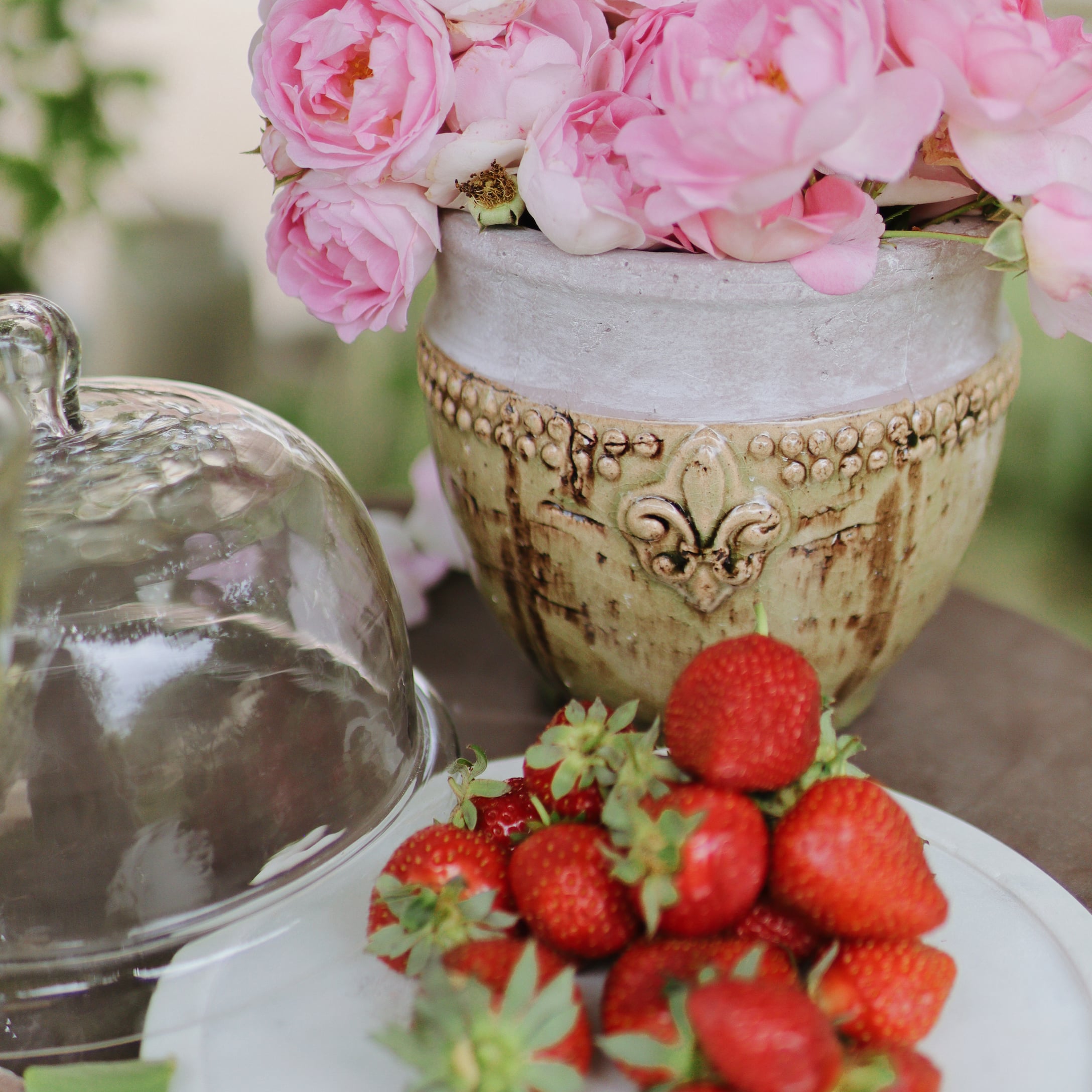 Pot en céramique avec fleurs roses et fraises fraîches sur une assiette blanche