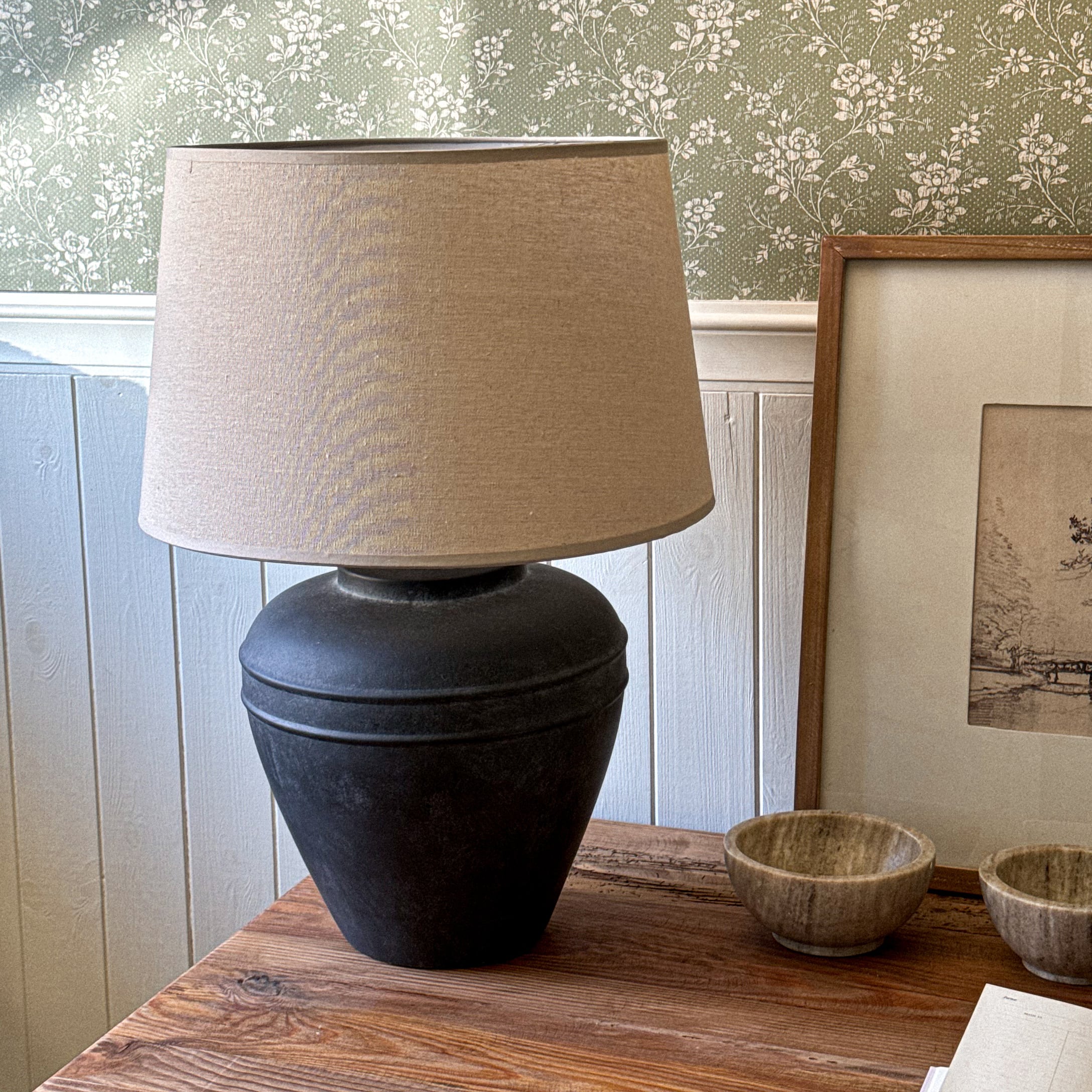 Lampe de table avec base en céramique noire et abat-jour beige sur une table en bois