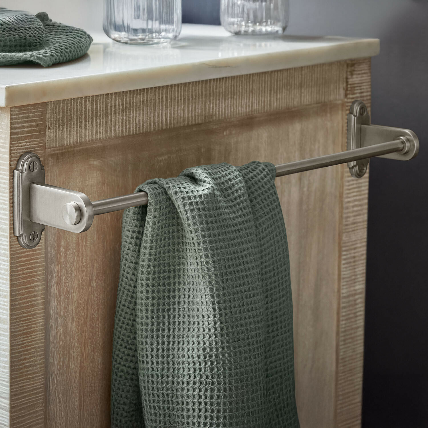 Porte-serviettes Virellane Porte-serviettes en métal avec serviette verte gaufrée suspendue sur un meuble en bois clair