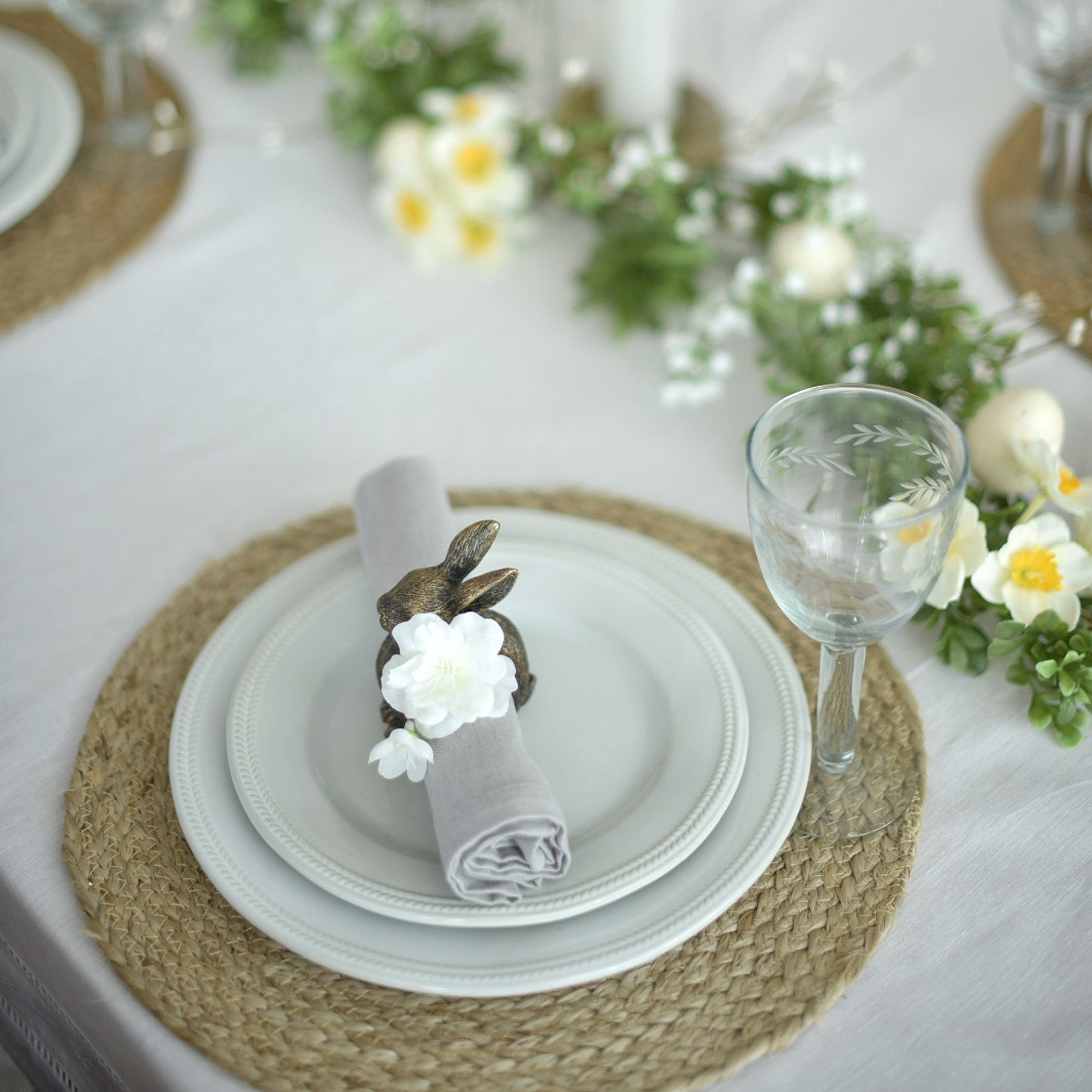 Service de table blanc avec napperon tressé, porte-serviette lapin et décoration florale délicate
