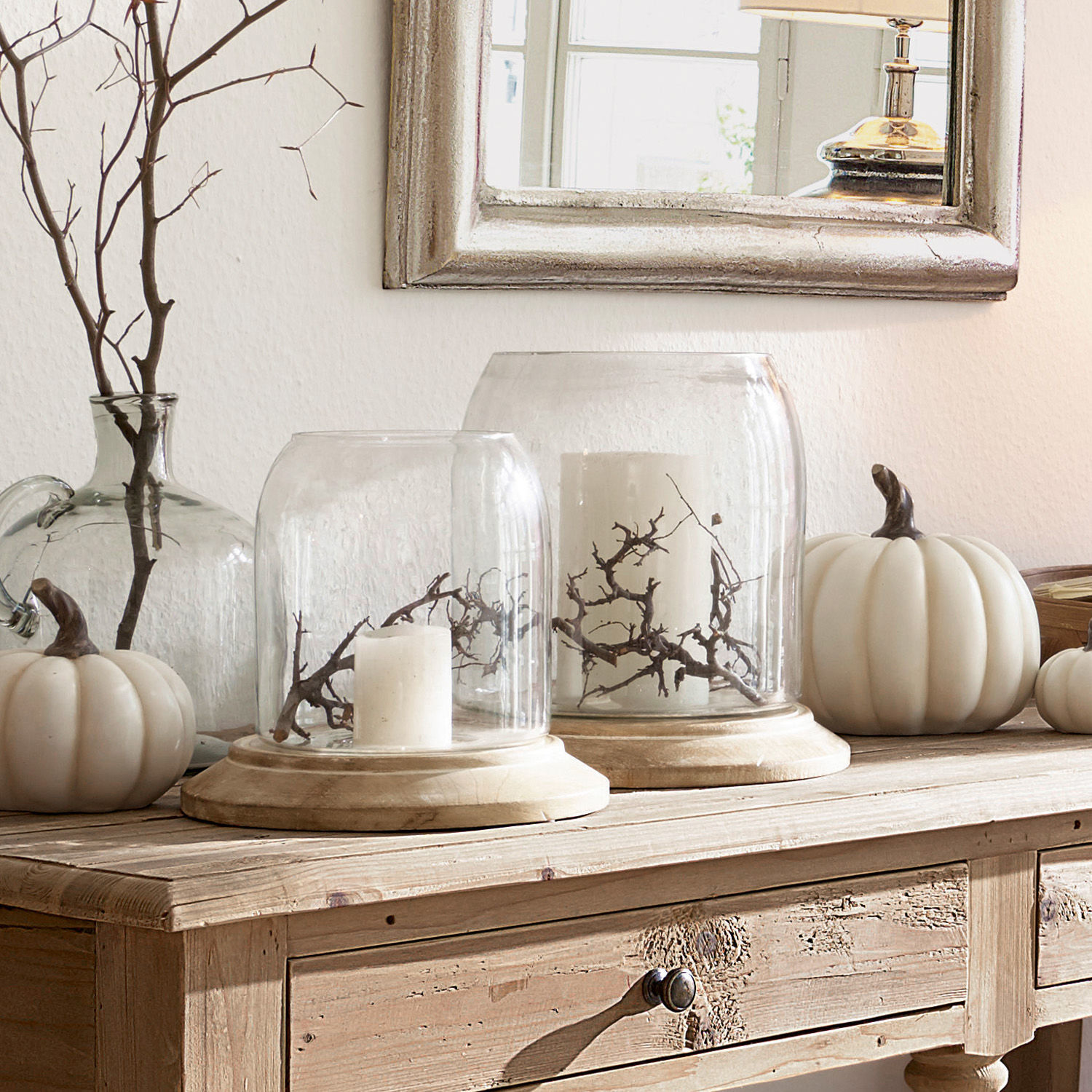 Lot de 2 photophores Bran Cloche en verre décorative sur socle en bois avec bougies blanches et branches sur une table en bois