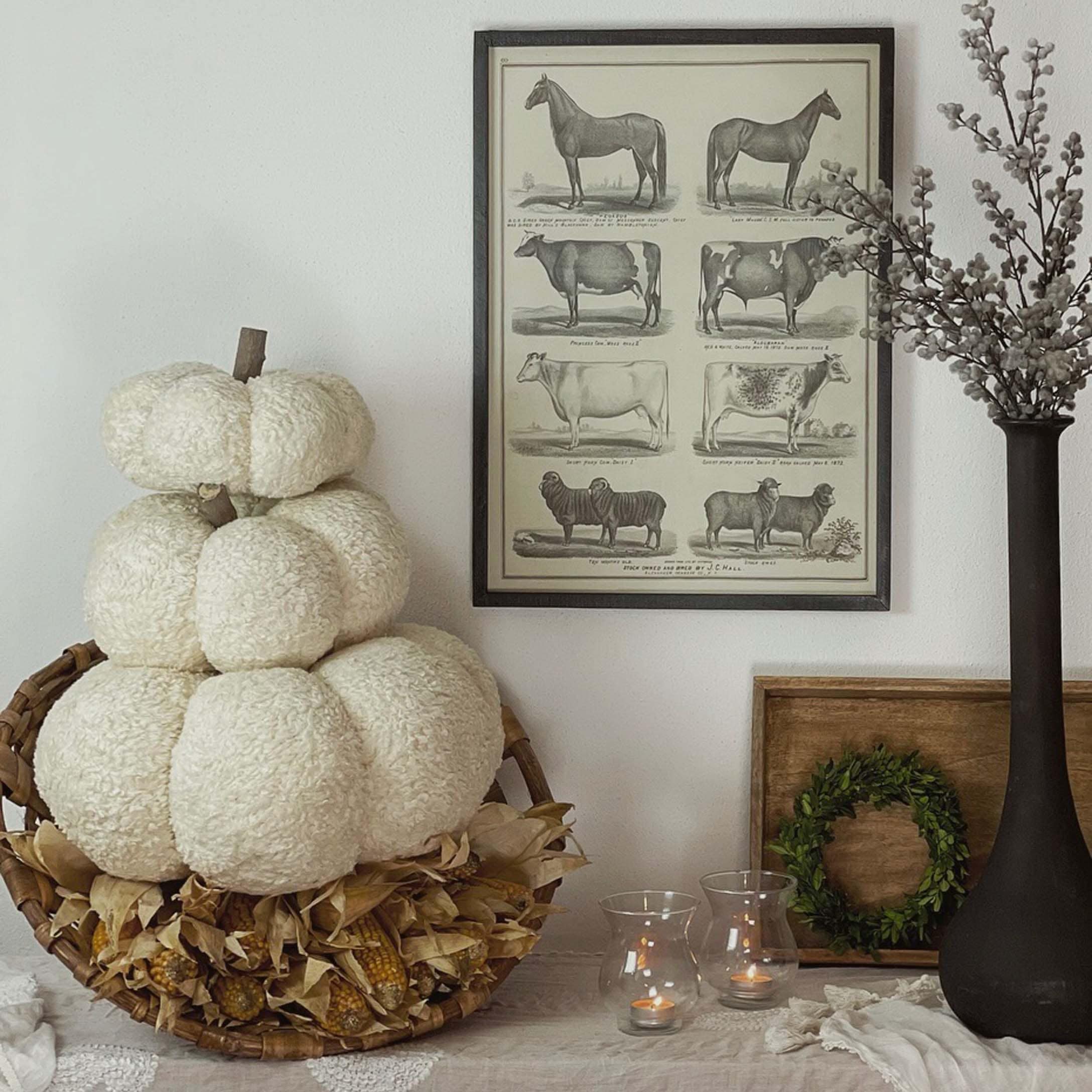Décoration d'automne avec citrouille blanche en peluche dans un panier en osier et bougies