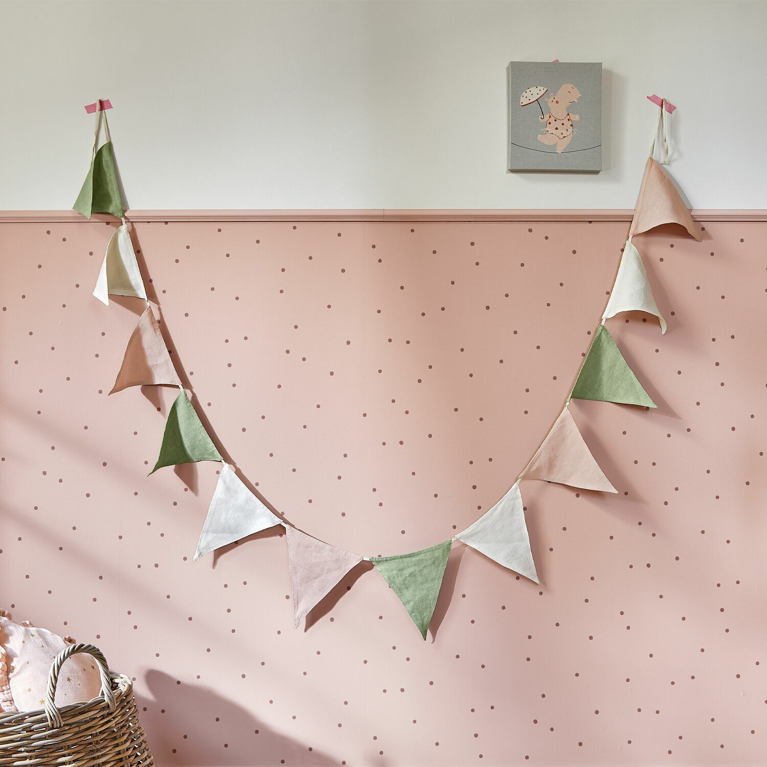 Guirlande à fanions Rêveline Guirlande de fanions triangulaires en lin aux couleurs pastel sur un mur rose à pois