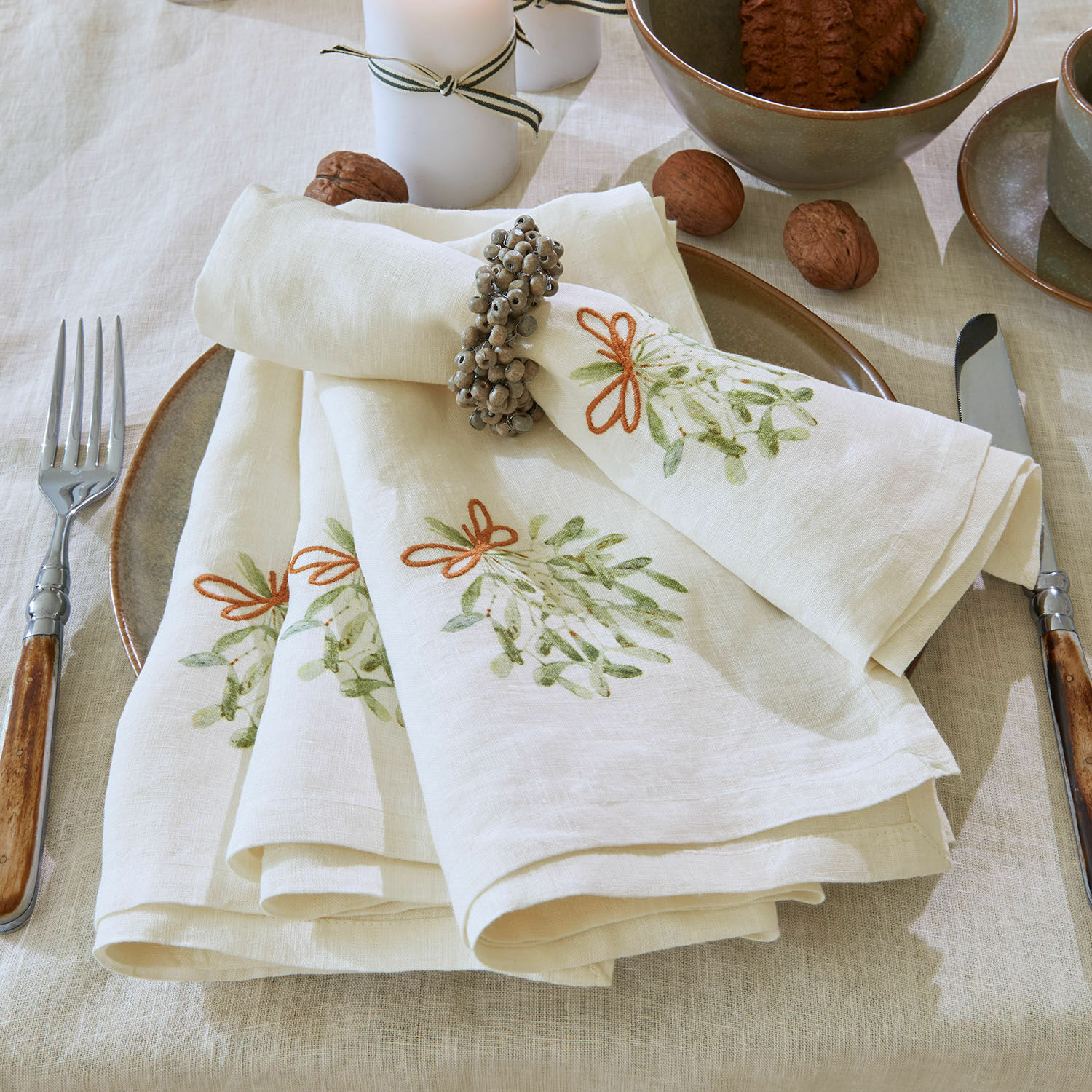 Lot de 4 serviettes de table Mistletoe Serviettes en lin crème avec motif vert et anneau sur table avec vaisselle et noix