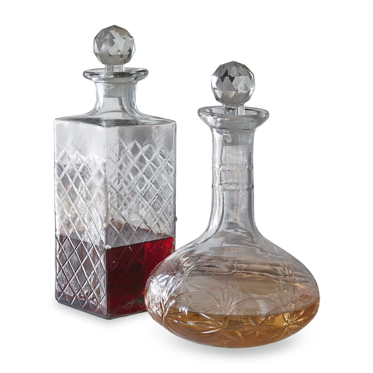 Lot de 2 carafes Dairine Ensemble de deux carafes en verre avec bouchons facettés, contenant des liquides rouge et ambré