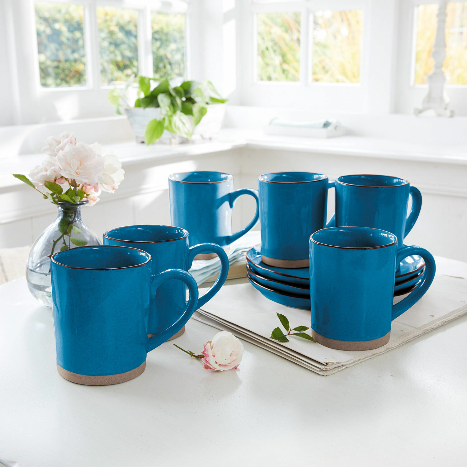 Lot de 6 tasses Biarré Ensemble de six mugs en céramique bleue avec base marron sur une table blanche dans une cuisine lumineuse