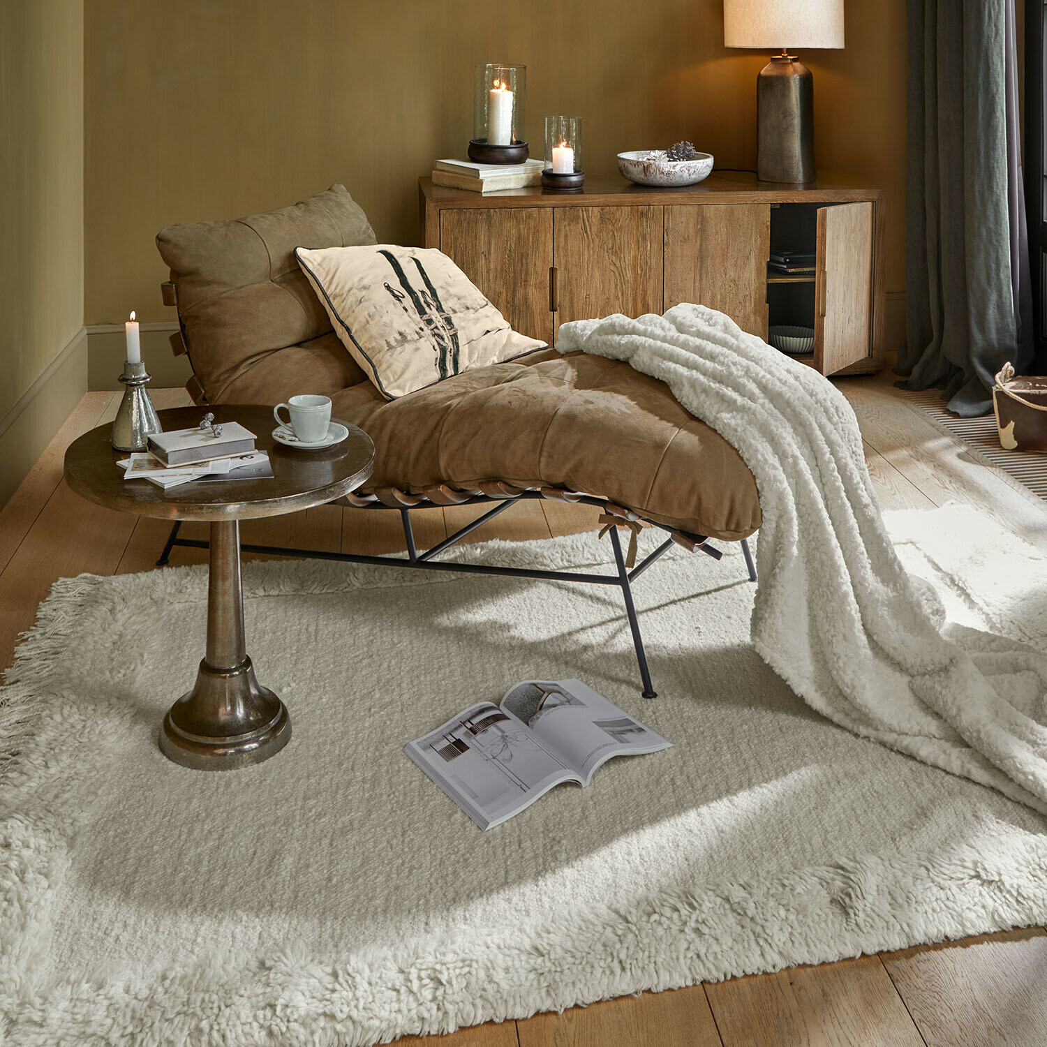 Fauteuil en cuir marron avec couverture blanche sur tapis crème dans un salon chaleureux