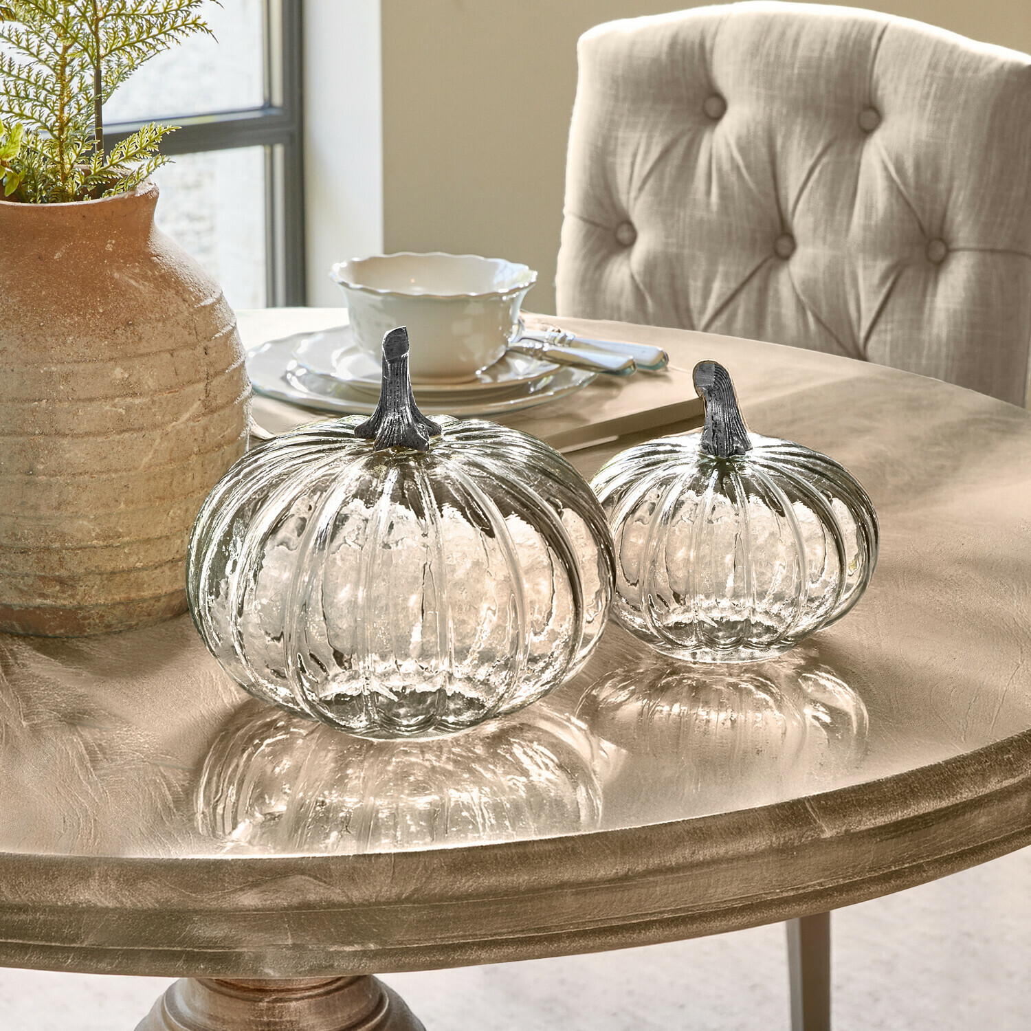 Lot de 2 citrouilles Perlouin Deux citrouilles en verre transparent avec tiges métalliques sur une table beige décorative