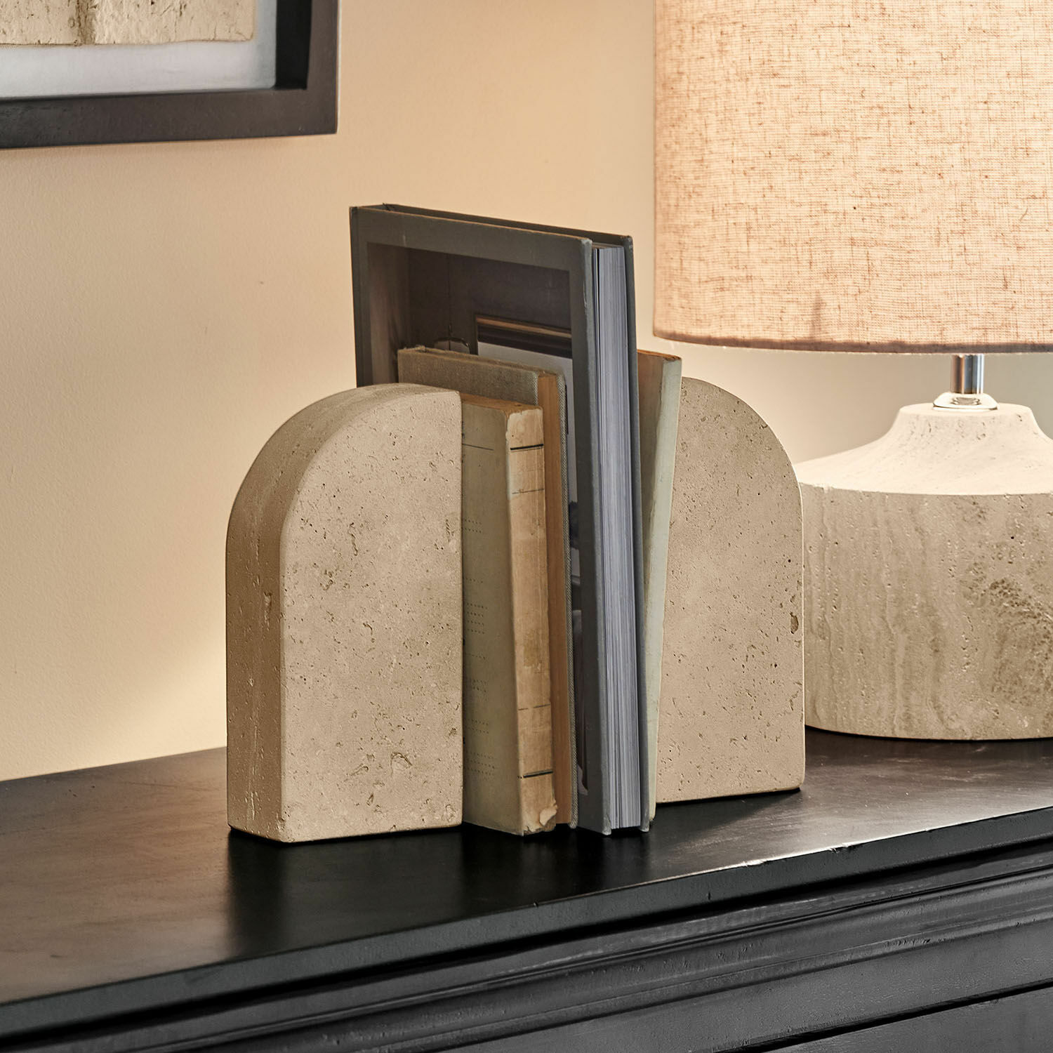 Lot de 2 serre-livres Caleneuve Serre-livres en pierre beige arrondie posés sur une étagère noire dans un salon moderne
