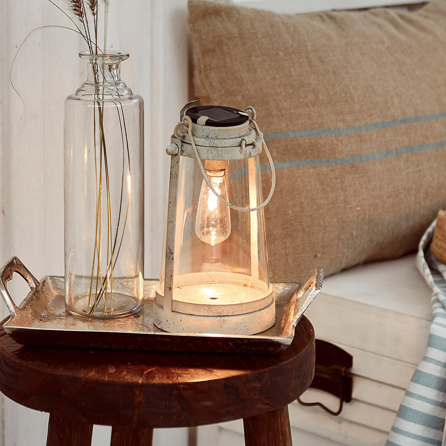 Lanterne solaire Chénens Lanterne blanche en métal avec verre transparent et ampoule sur une table en bois avec décoration