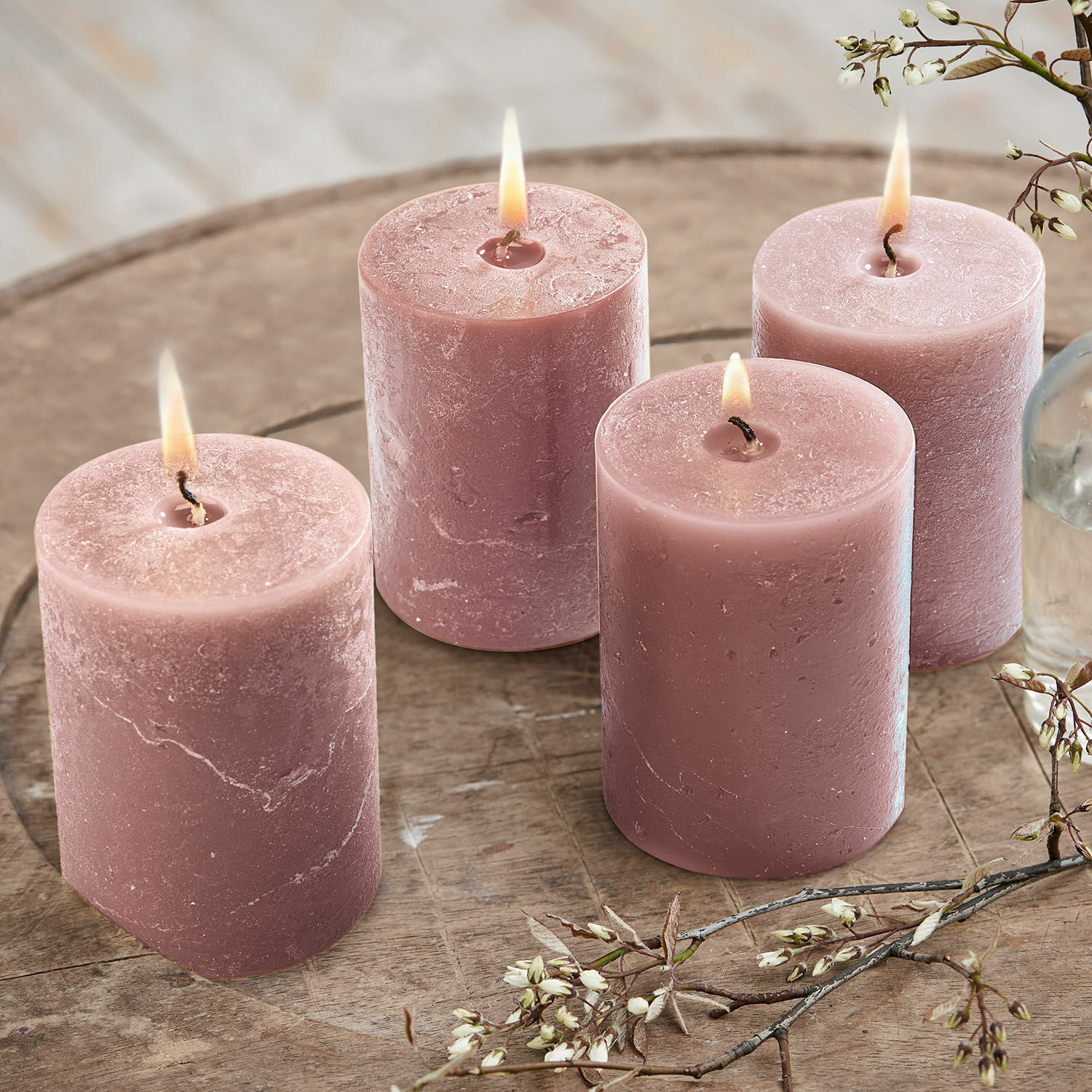 Lot de 4 bougies Virrans Ensemble de quatre bougies roses en cire sur une table en bois avec décoration florale