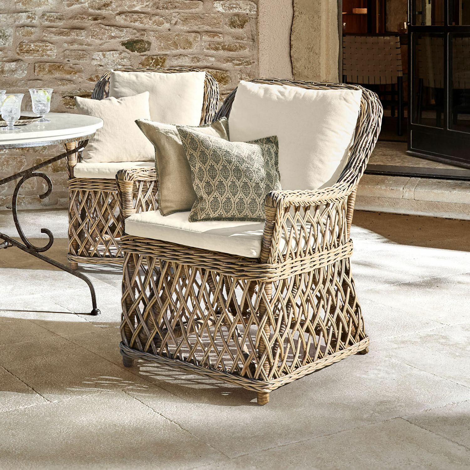 Fauteuil Nesvryn Fauteuil en rotin naturel avec coussins crème et coussins décoratifs pour un confort extérieur élégant.
