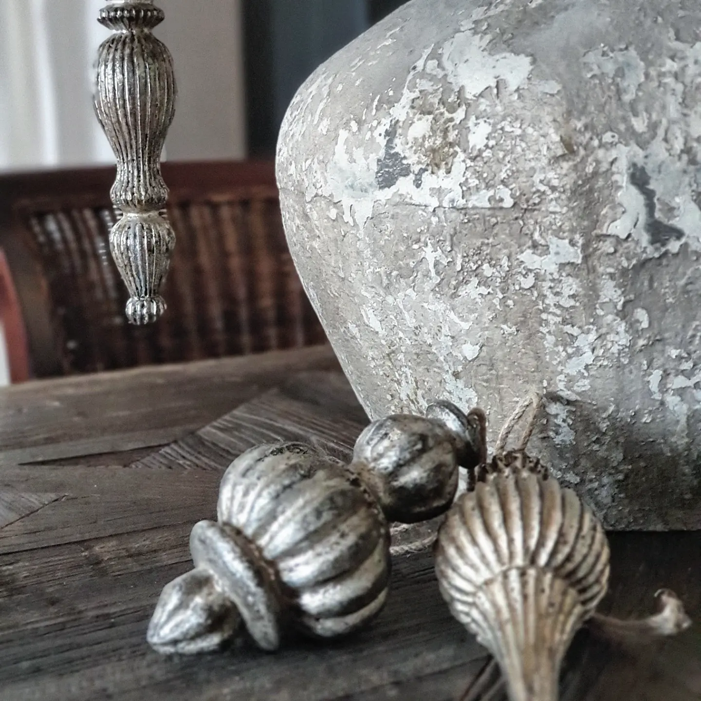 Décorations argentées en métal sur table en bois à côté d'un vase en céramique patiné