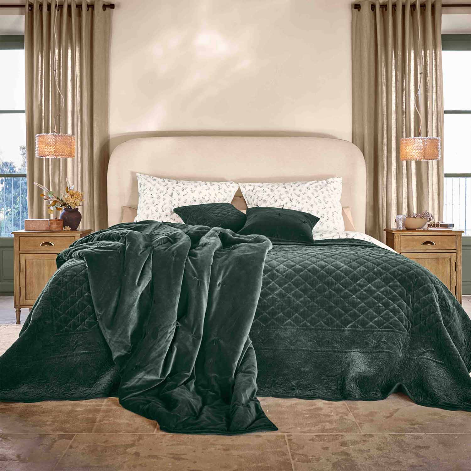 Couverture et coussins vert foncé en velours sur lit avec tête de lit beige dans chambre élégante