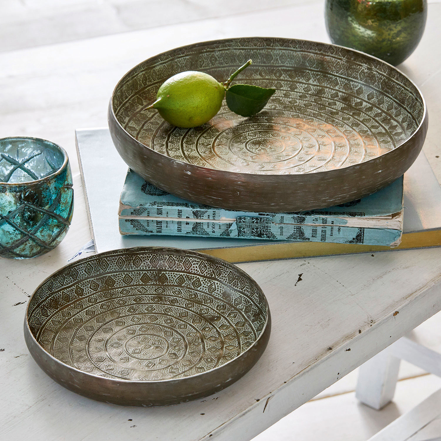 Lot de 2 plateaux Birse Ensemble de deux bols en métal argenté vieilli avec motifs décoratifs sur une table blanche