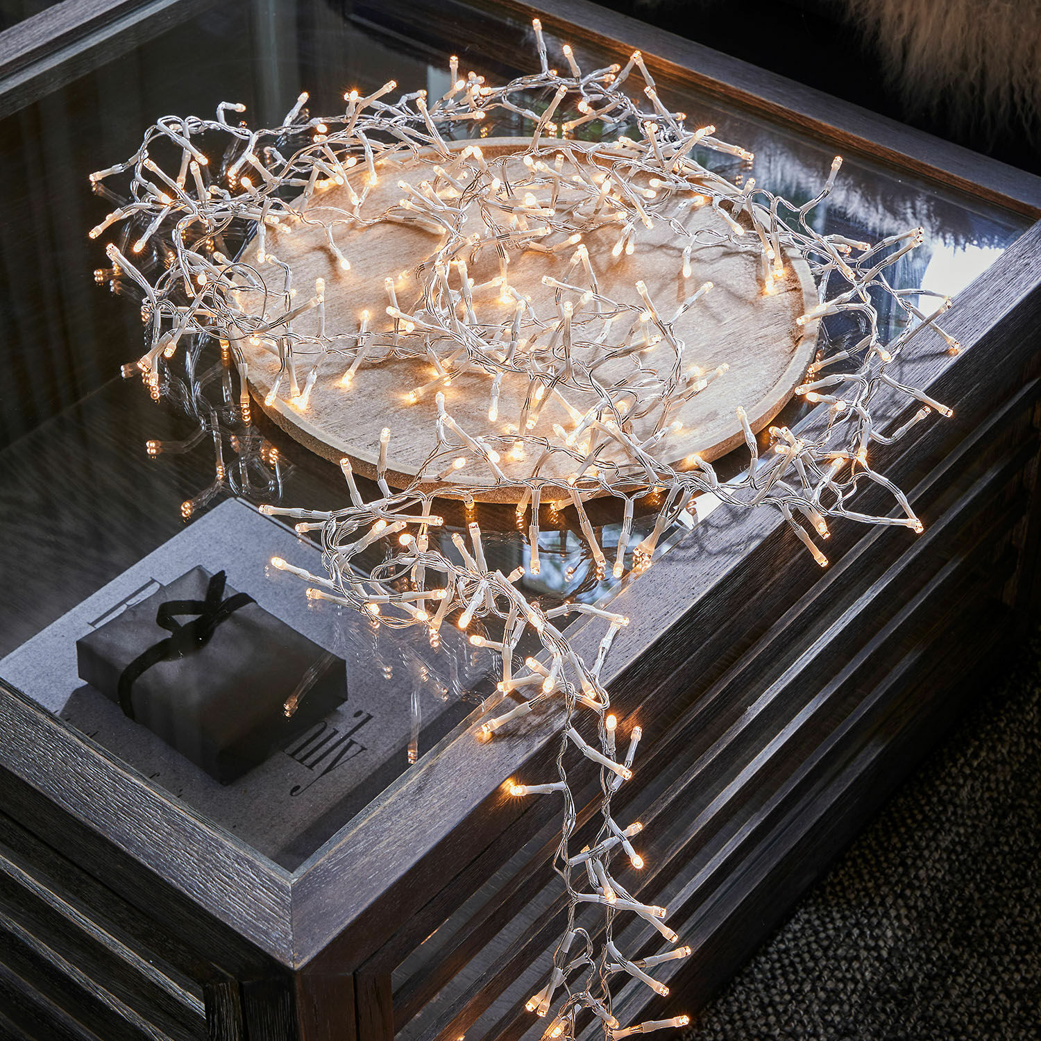Guirlande lumineuse Aedara Guirlande lumineuse LED à lumière chaude sur fil transparent posée sur un plateau en bois sur une table en verre