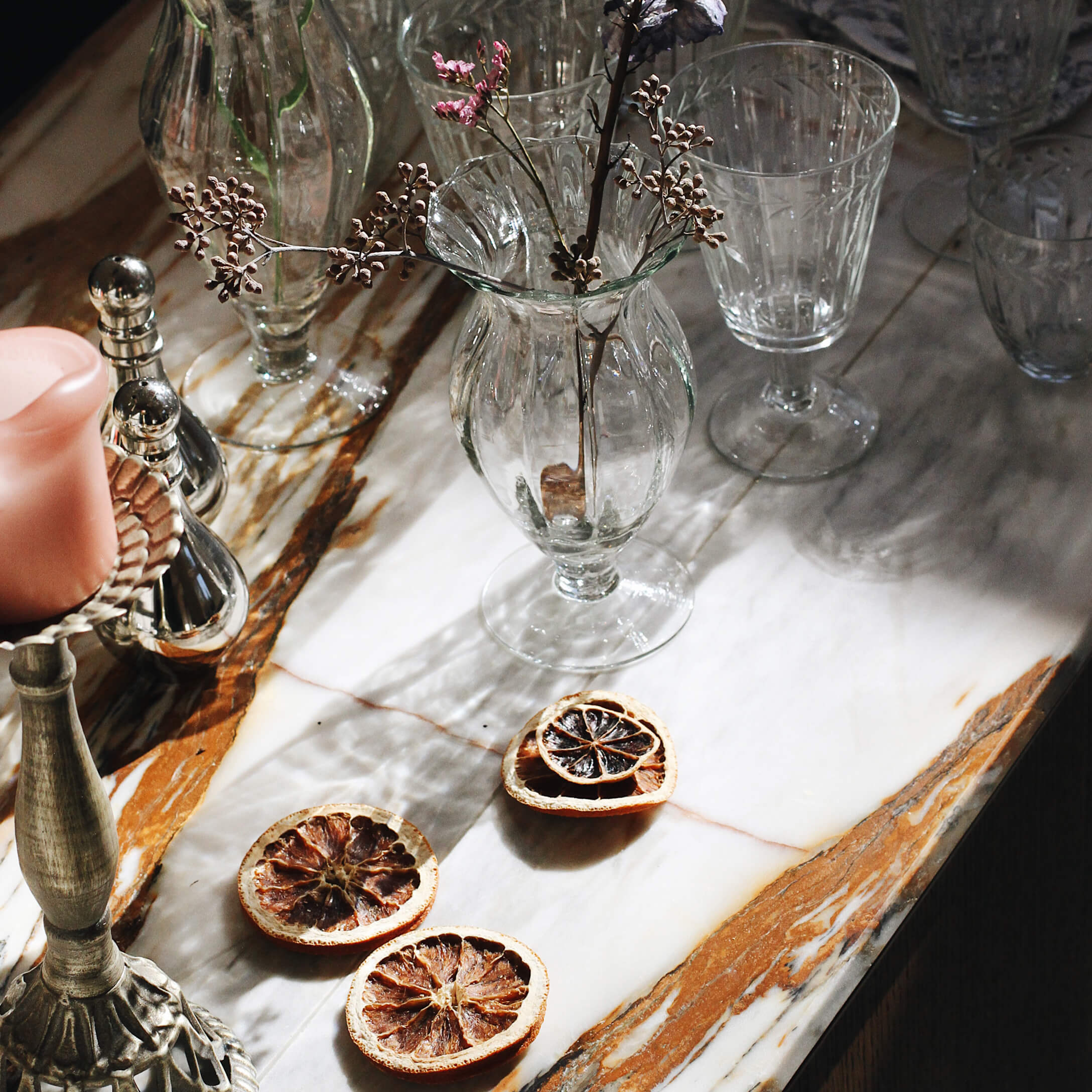 Vase en verre avec fleurs séchées sur un plateau en marbre avec tranches de fruits décoratives