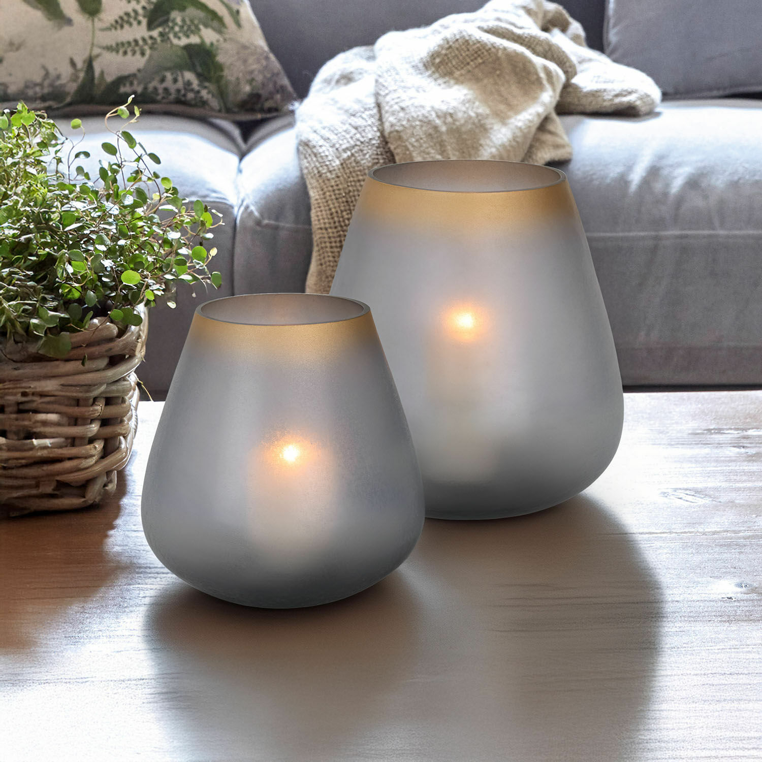 Lot de 2 photophores Nilorav Deux photophores en verre givré gris sur une table en bois dans un salon avec plante et canapé