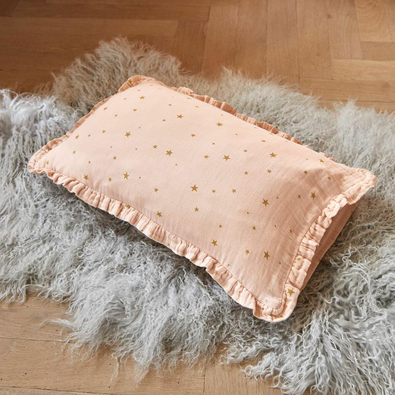 Housse de coussin Vianne Coussin rose en coton avec volants et étoiles dorées sur tapis en fausse fourrure grise