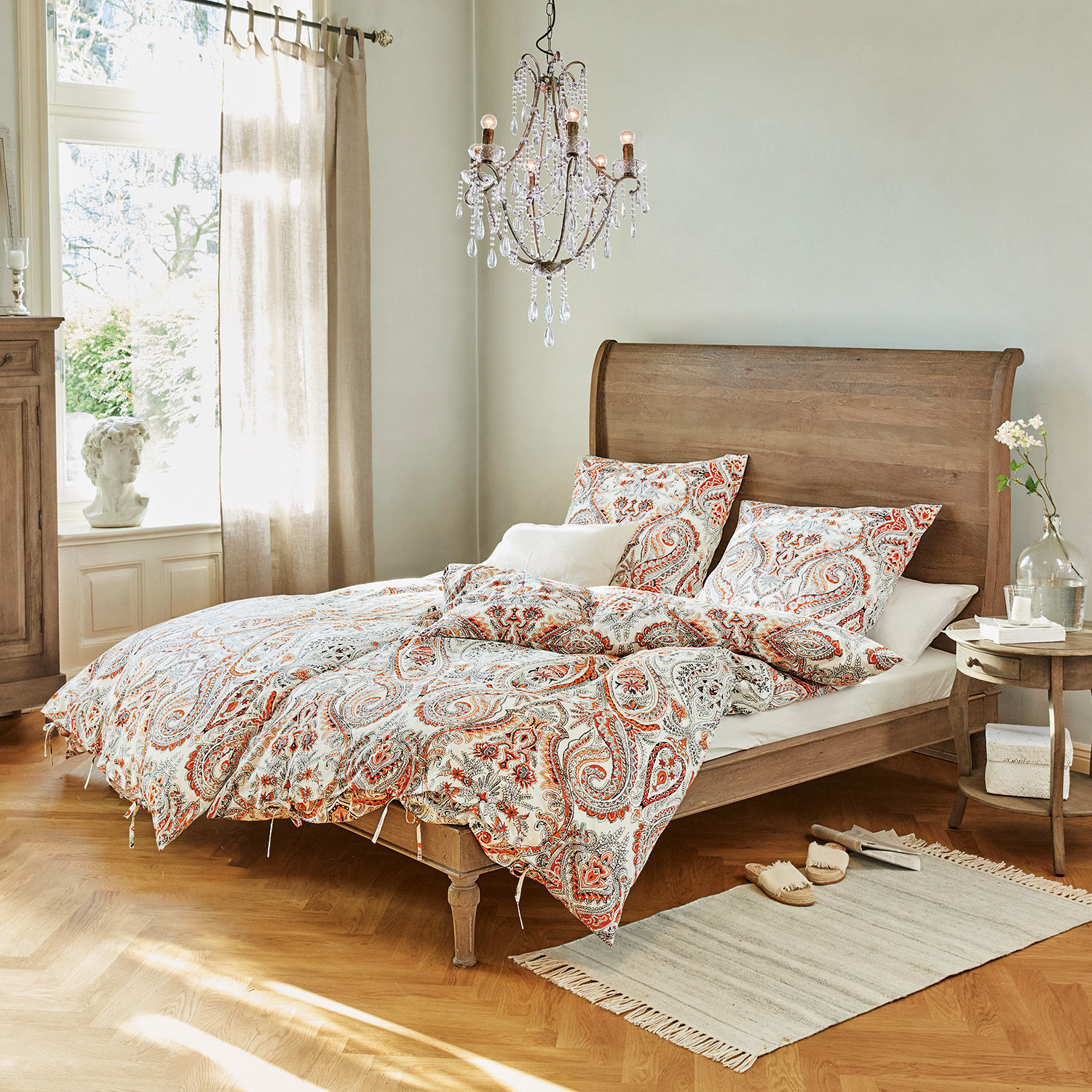 Lit Saint-Germier Chambre avec lit en bois et linge de lit à motif paisley rouge et blanc, tapis et lustre en cristal