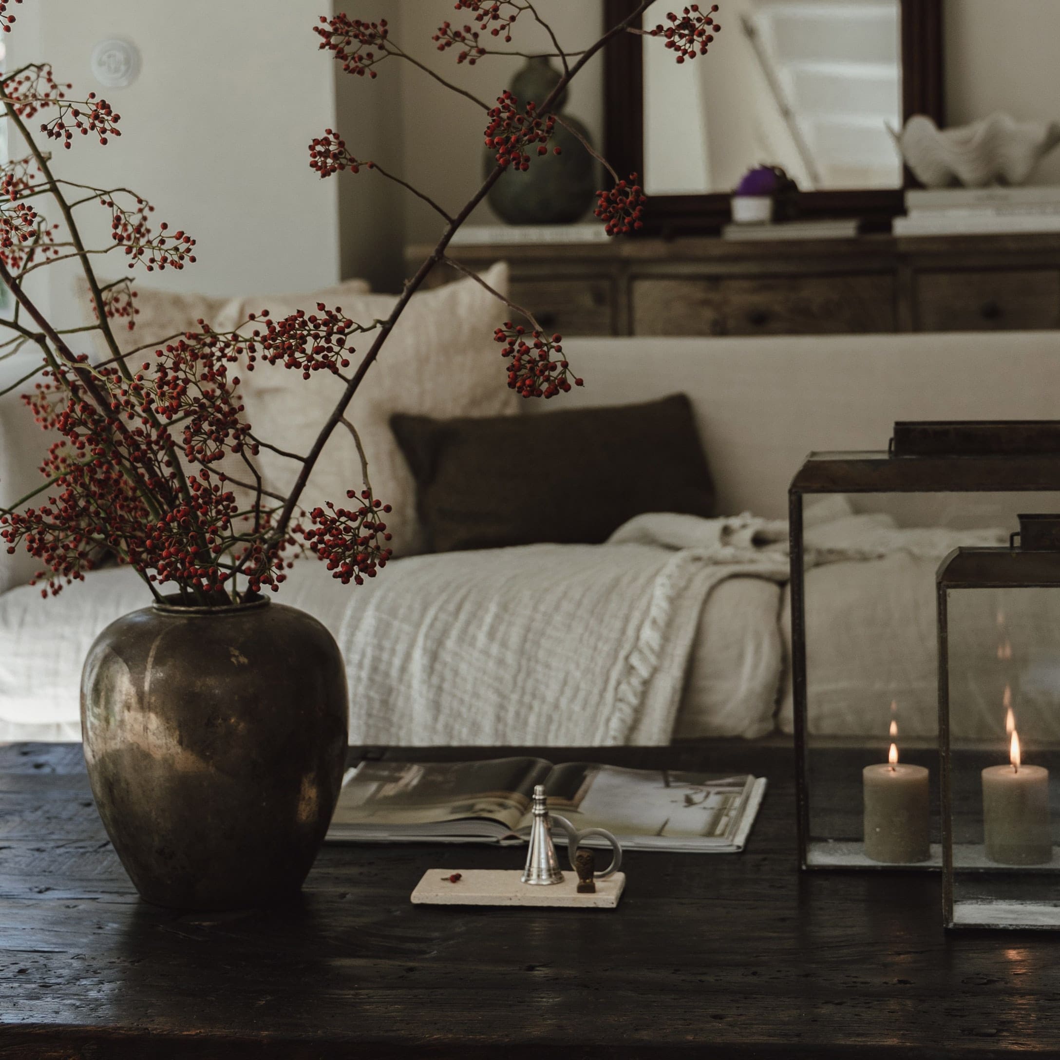 Vase décoratif avec branches rouges sur une table en bois foncé dans un salon chaleureux
