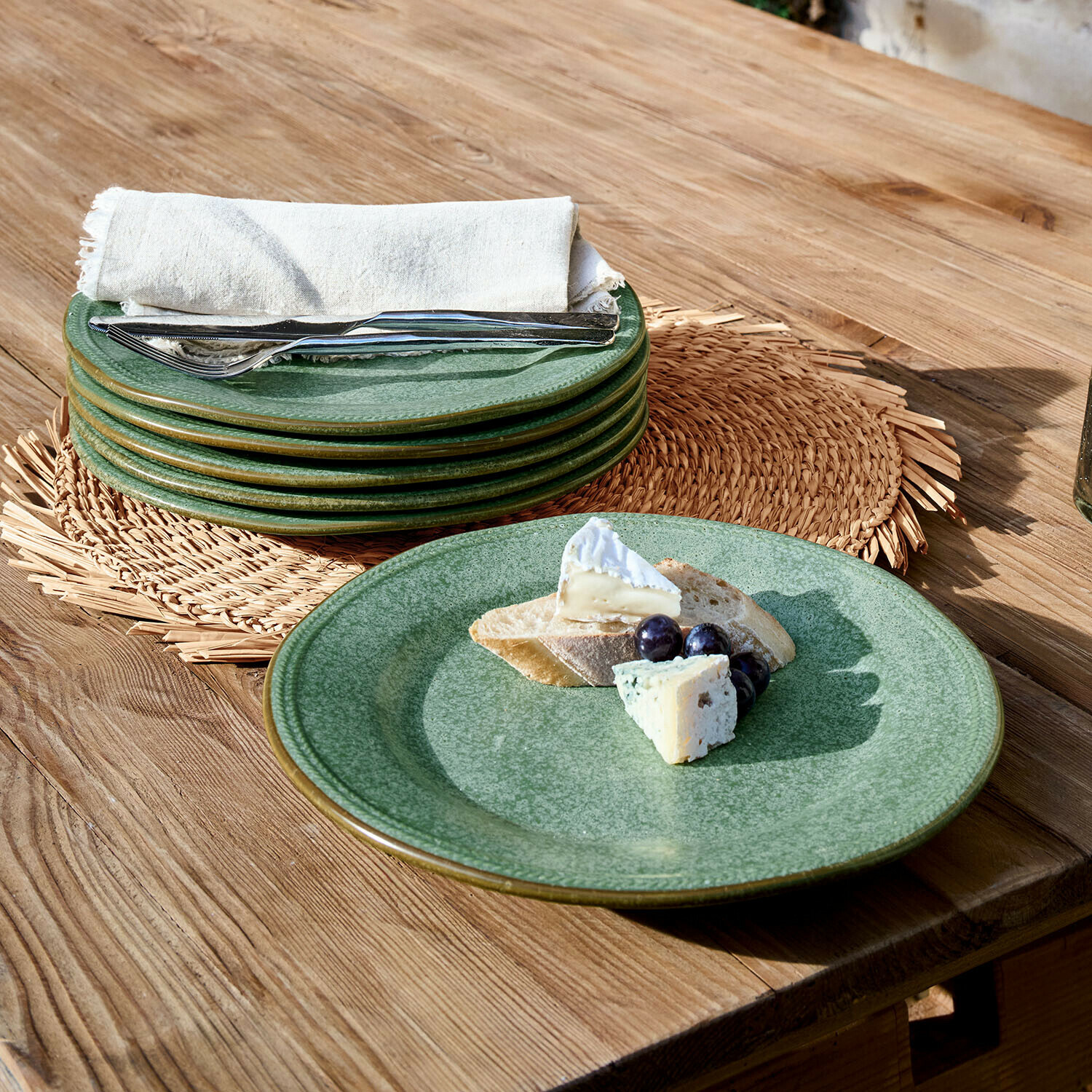 Ensemble d'assiettes en céramique verte sur table en bois avec fromage, raisins et pain