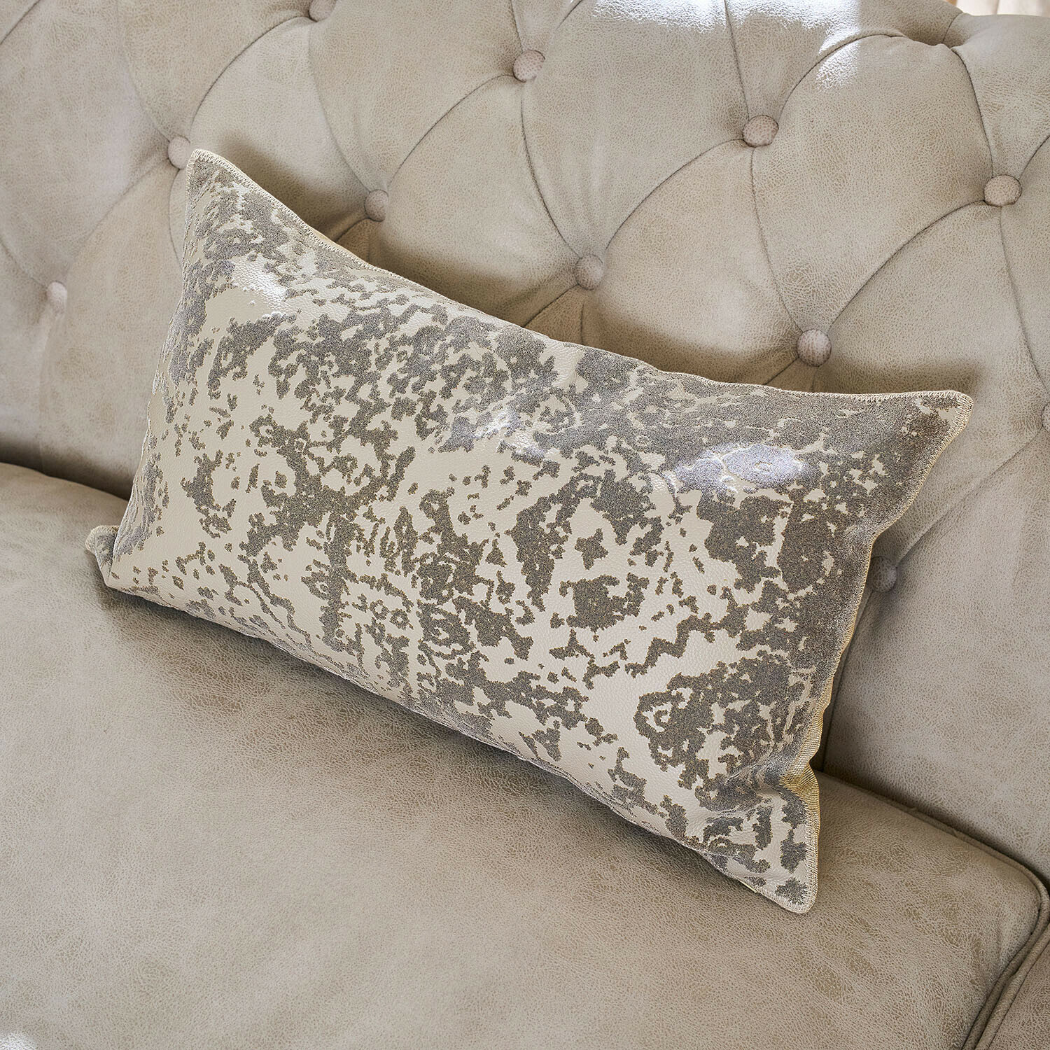 Housse de coussin Cressley Coussin décoratif rectangulaire avec motif gris et beige sur un canapé beige clair capitonné