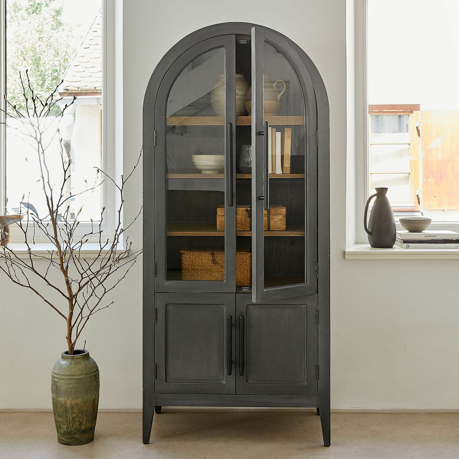 Armoire Chaloraine Vitrine noire en bois avec portes vitrées et étagères pour décorations et livres dans un salon