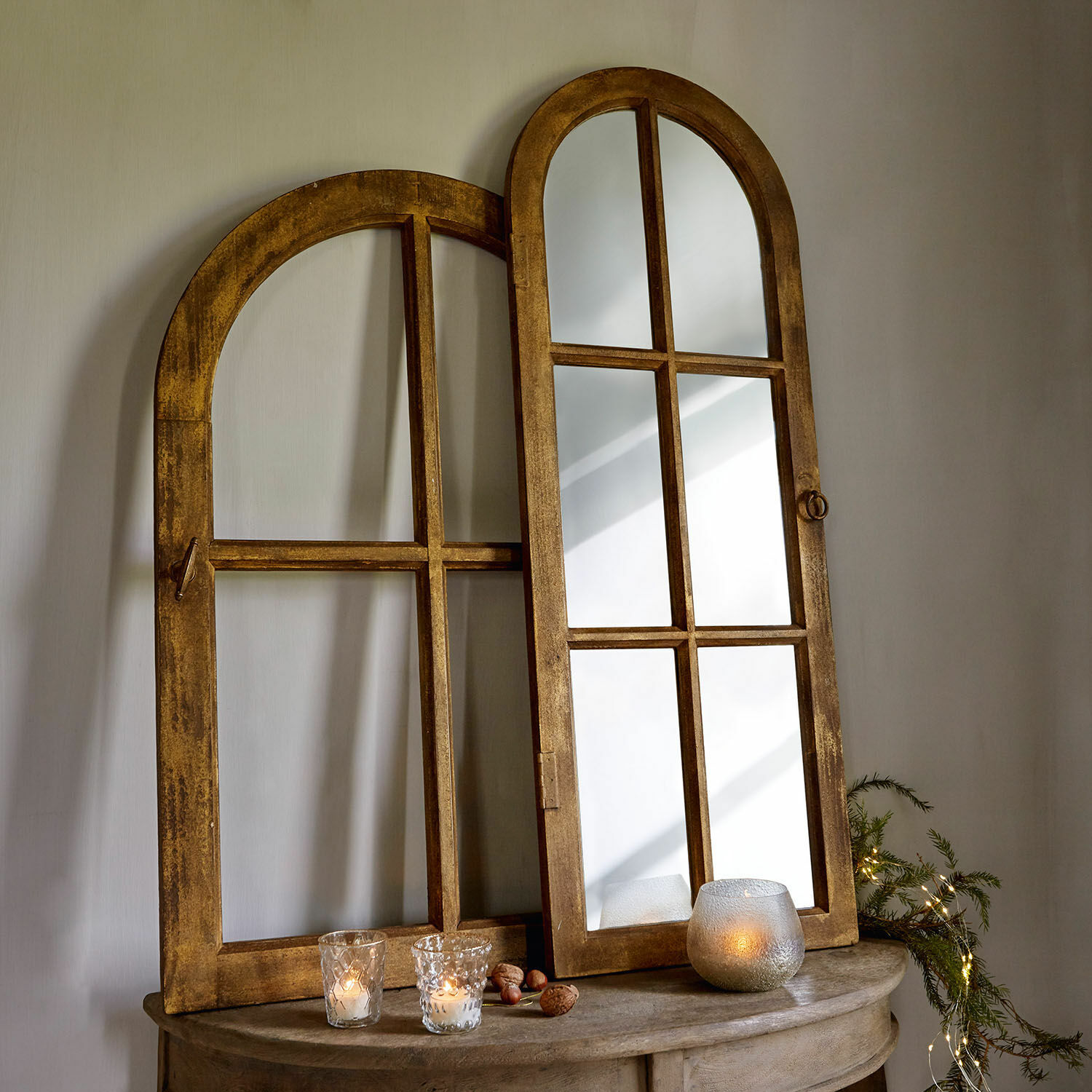 Miroir en bois à cadre arrondi couleur miel posé sur une table avec bougies et décorations naturelles