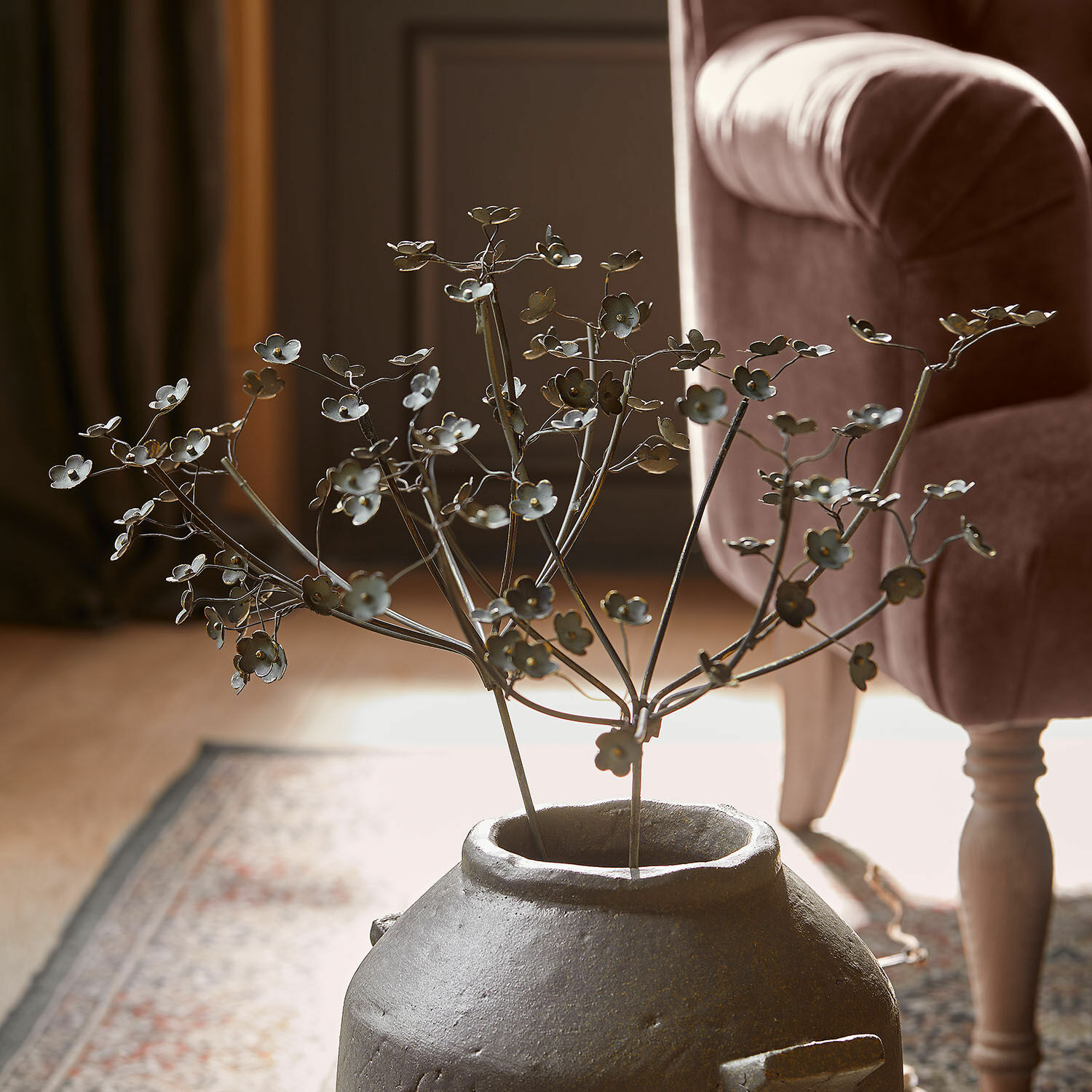 Lot de 2 fleurs décoratives Basmirah Branche décorative en métal avec fleurs dans un vase en céramique gris sur tapis dans un salon
