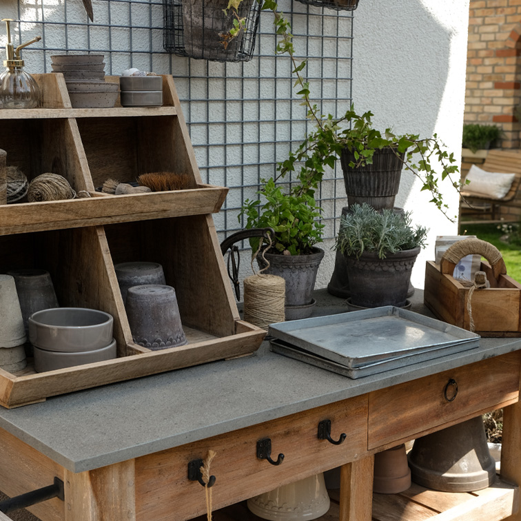 Table de jardin en bois avec outils de plantation et pots en terre cuite dans des tons naturels, décor extérieur