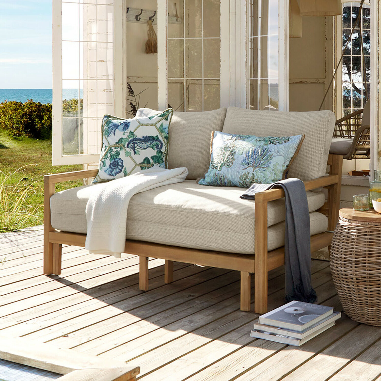Canapé convertible Tjorna Canapé beige clair avec structure en bois sur terrasse ensoleillée avec vue sur jardin et mer