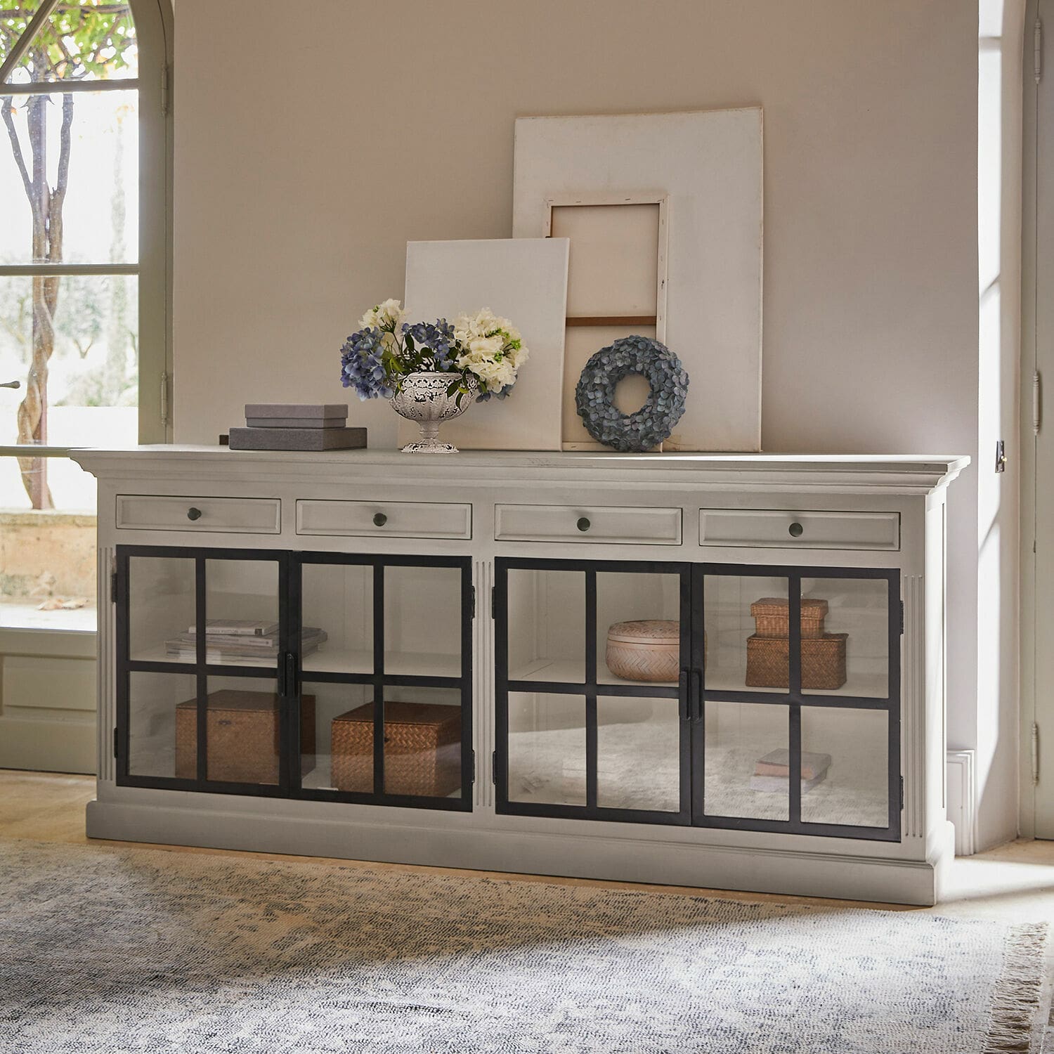 Vitrine Pratola Buffet en bois blanc avec portes vitrées noires et décorations sur le dessus dans un salon