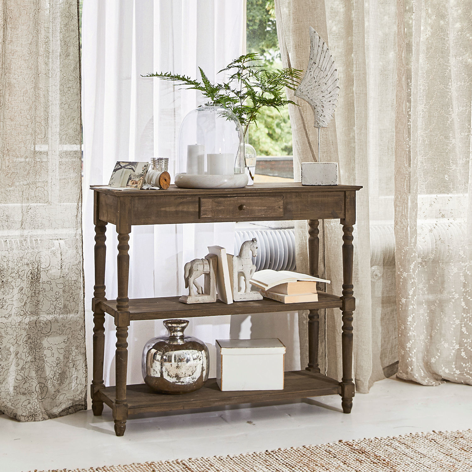 Console Roubaix Table en bois brun avec tiroir et étagères, décorations et livres dans un intérieur lumineux