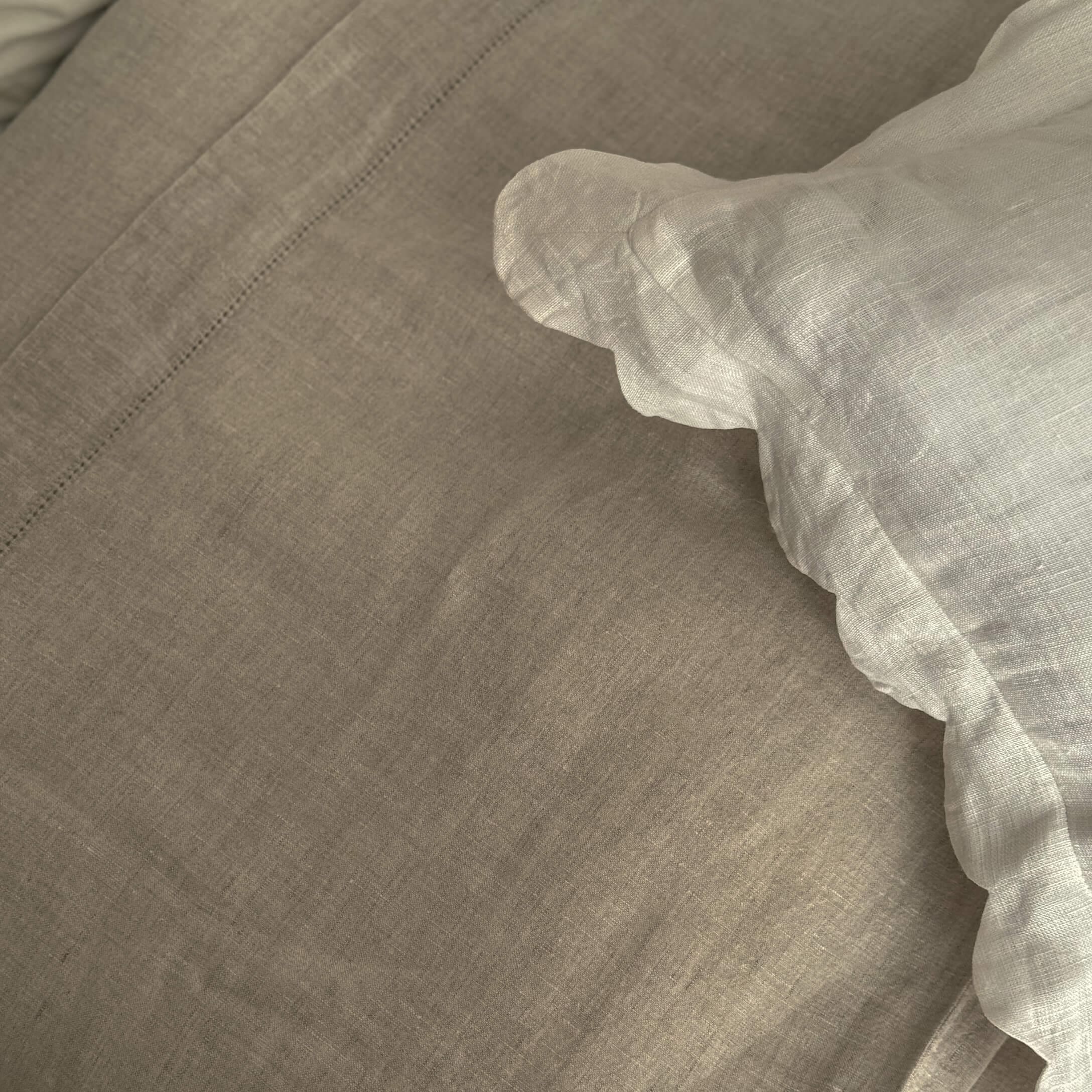 Linge de lit en lin beige et blanc avec texture naturelle pour une chambre confortable