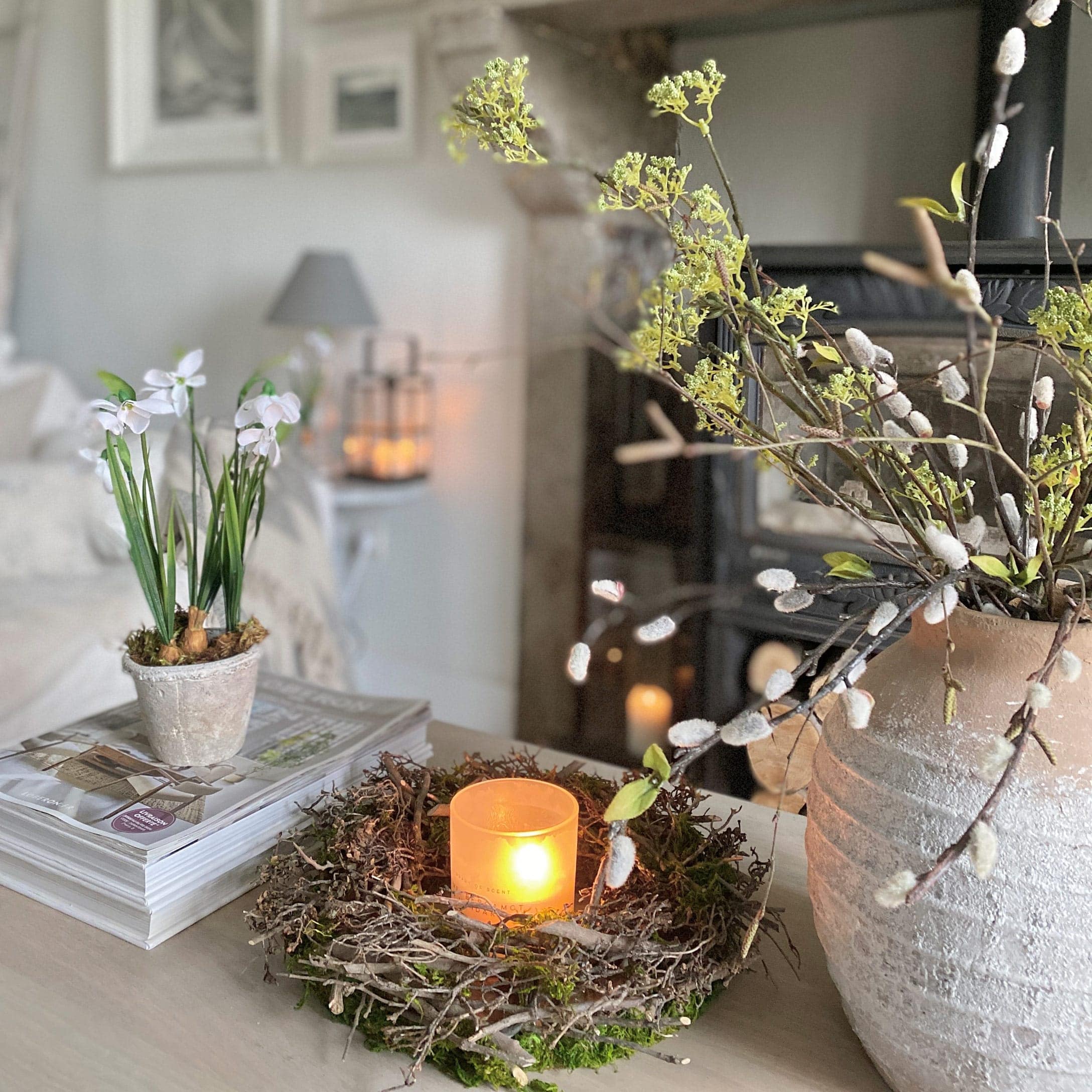 Couronne décorative en branches avec bougie dans un photophore en verre sur table dans un intérieur clair