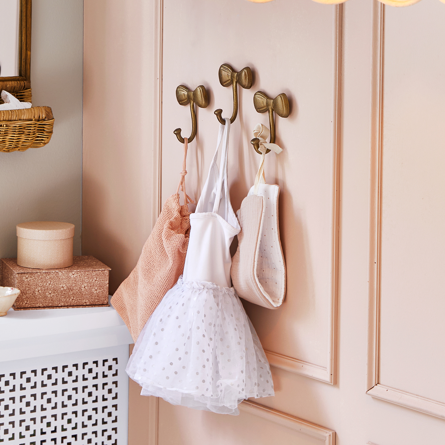 Crochets muraux dorés en forme de nœud sur mur rose avec vêtements d'enfant suspendus