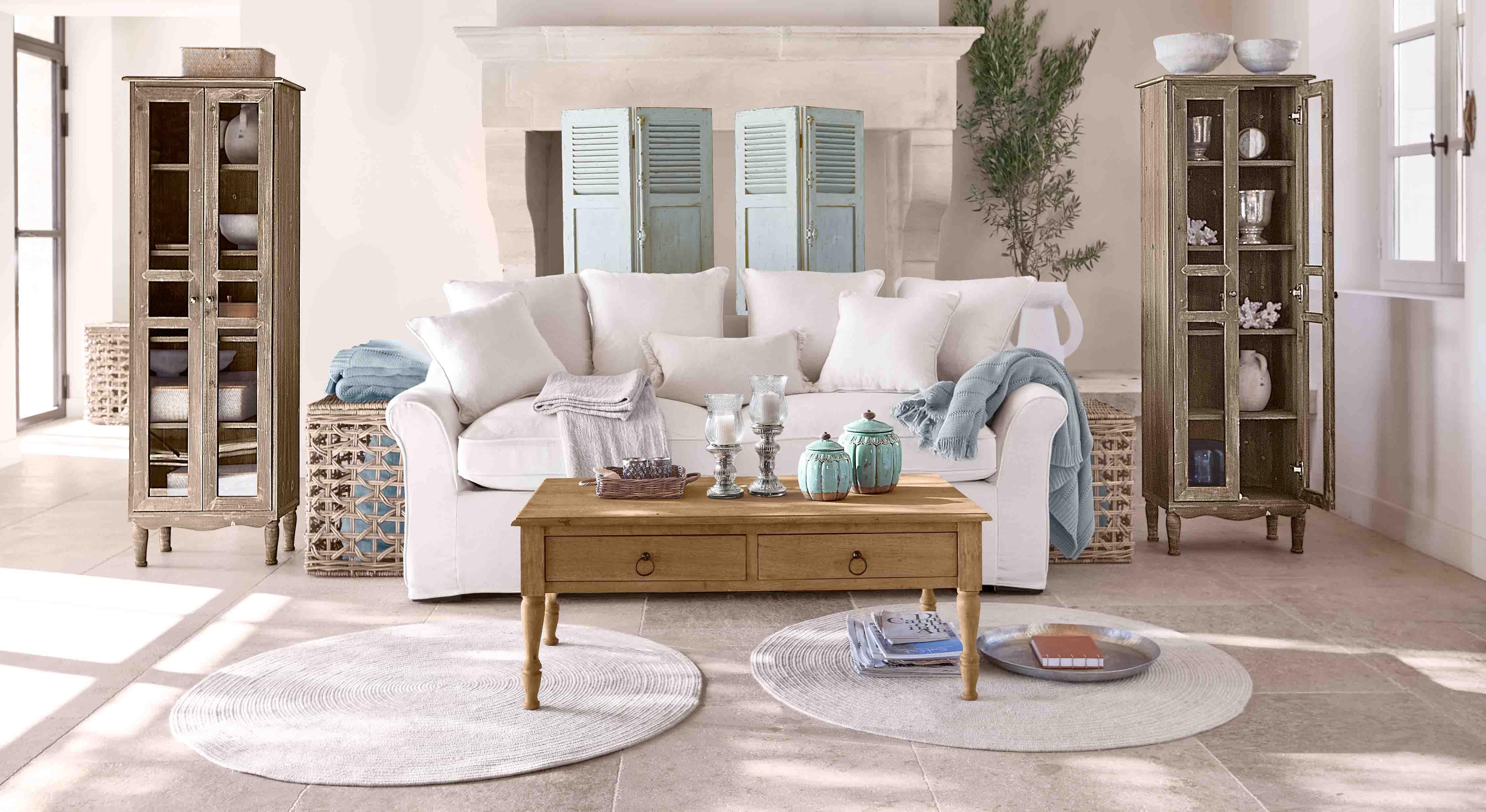 Salon chaleureux avec canapé blanc, table basse en bois et deux vitrines en bois style vintage