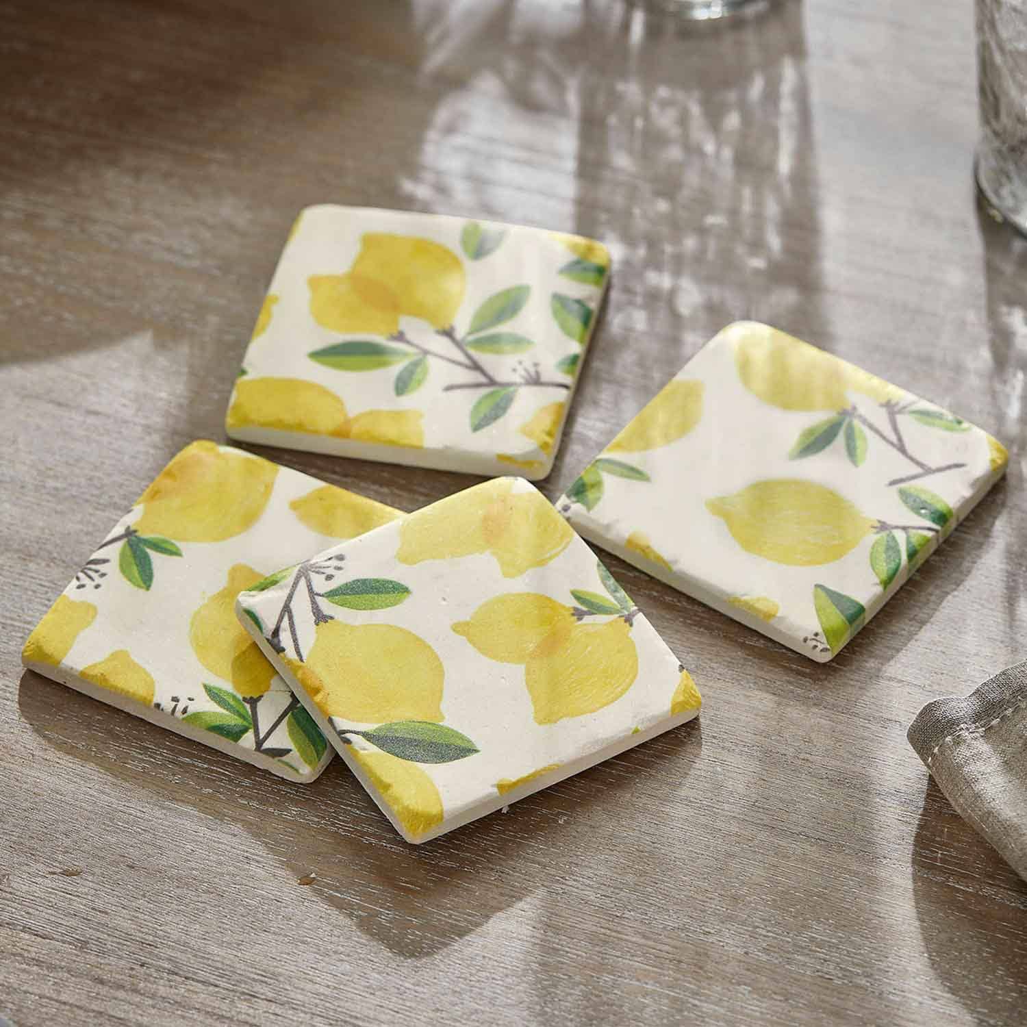 Dessous de verre en céramique avec motif citrons jaunes et feuilles vertes sur fond clair sur table en bois