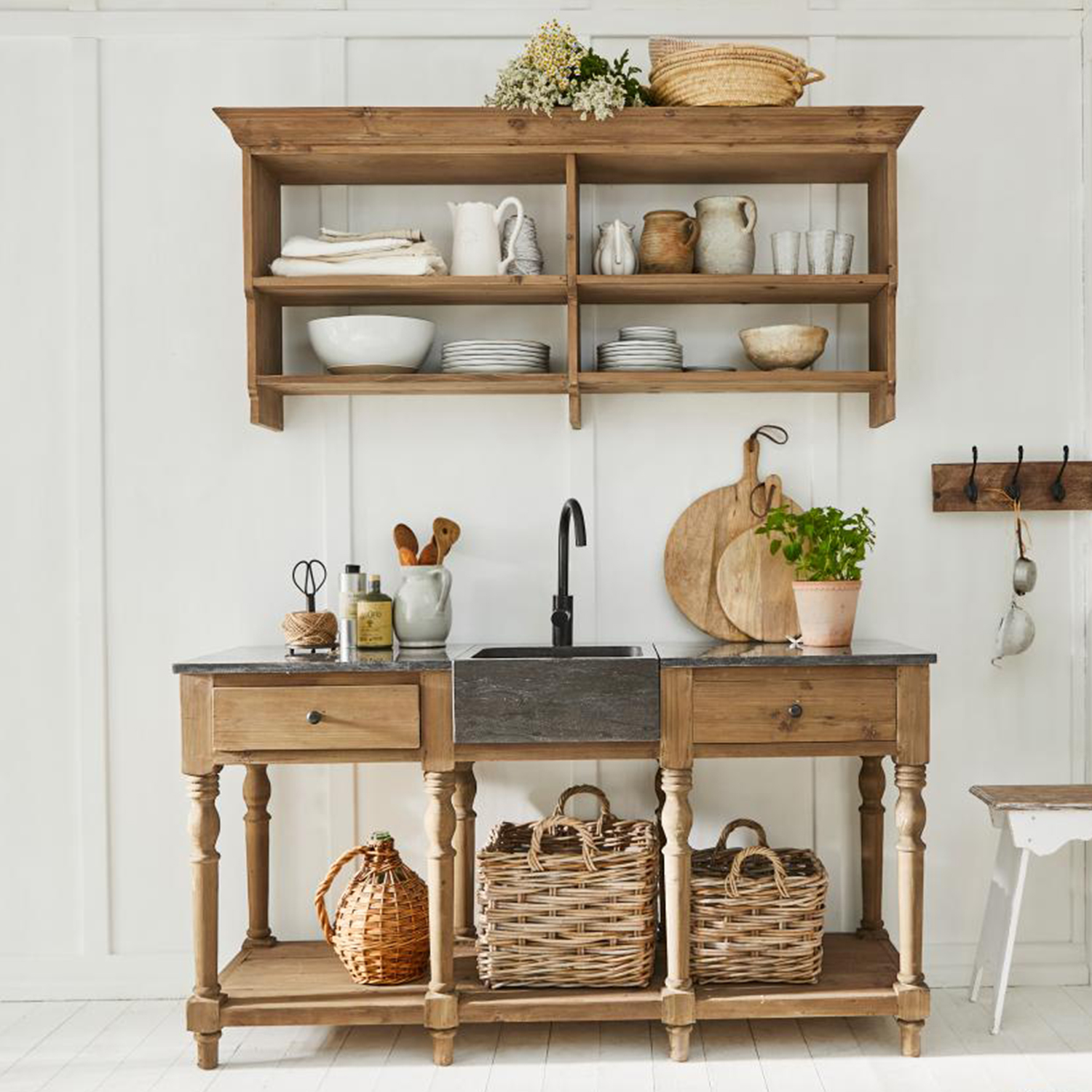 Cuisine rustique en bois avec évier noir et paniers en osier sur mur blanc lumineux