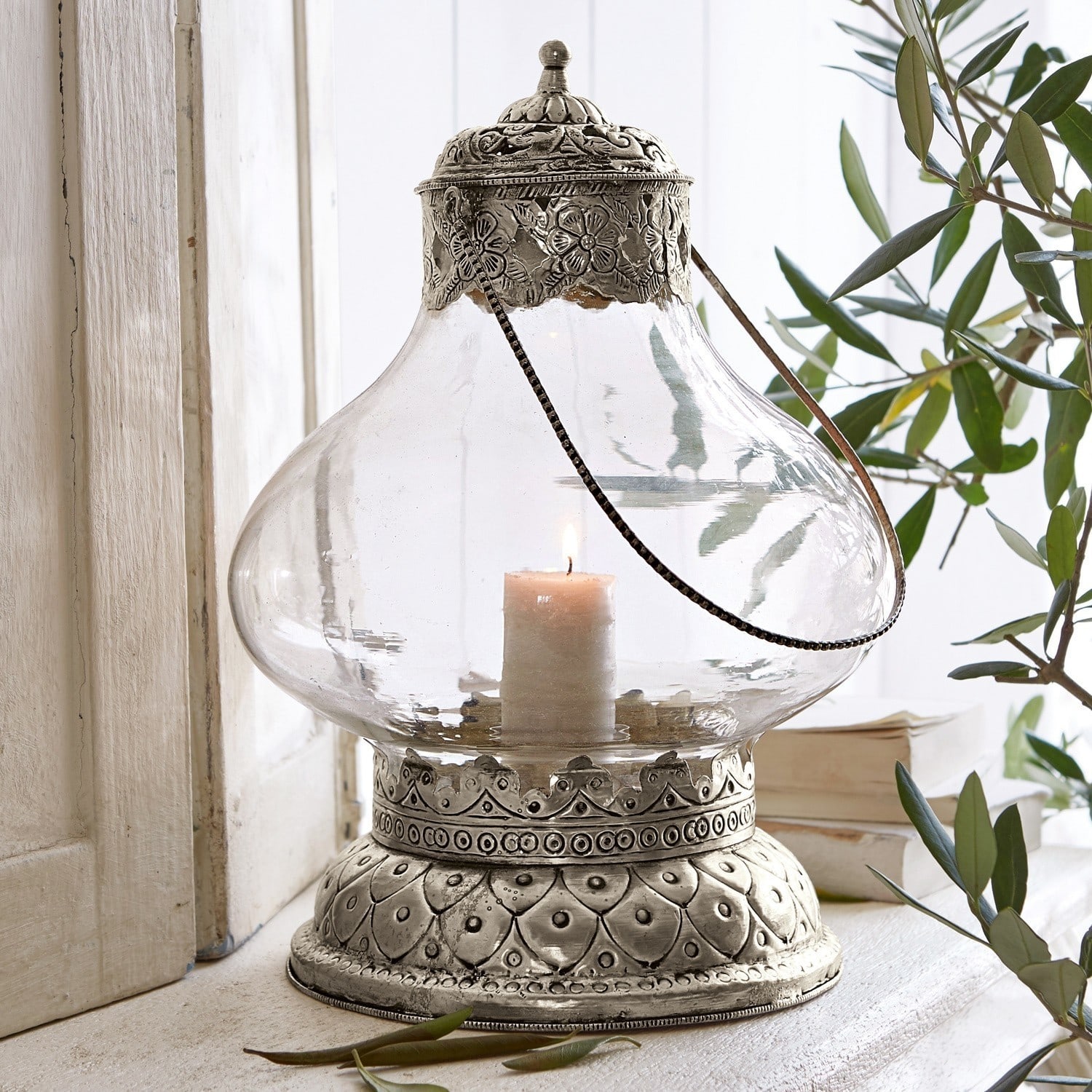 Lanterne Kaela Lanterne en verre avec base et couvercle en métal argenté à motifs floraux, bougie allumée à l'intérieur