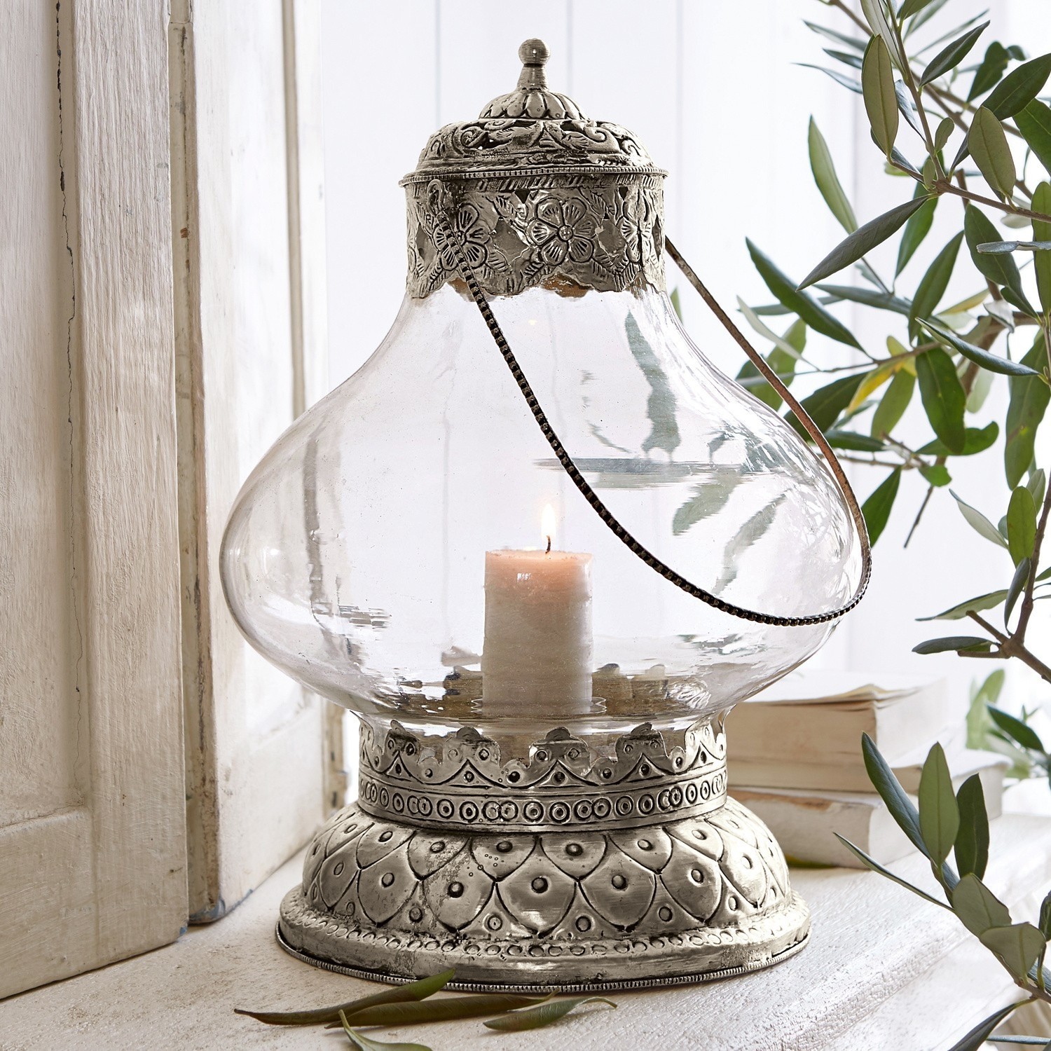 Lanterne Kaela Lanterne en verre avec base et couvercle en métal argenté à motifs floraux, bougie allumée à l'intérieur