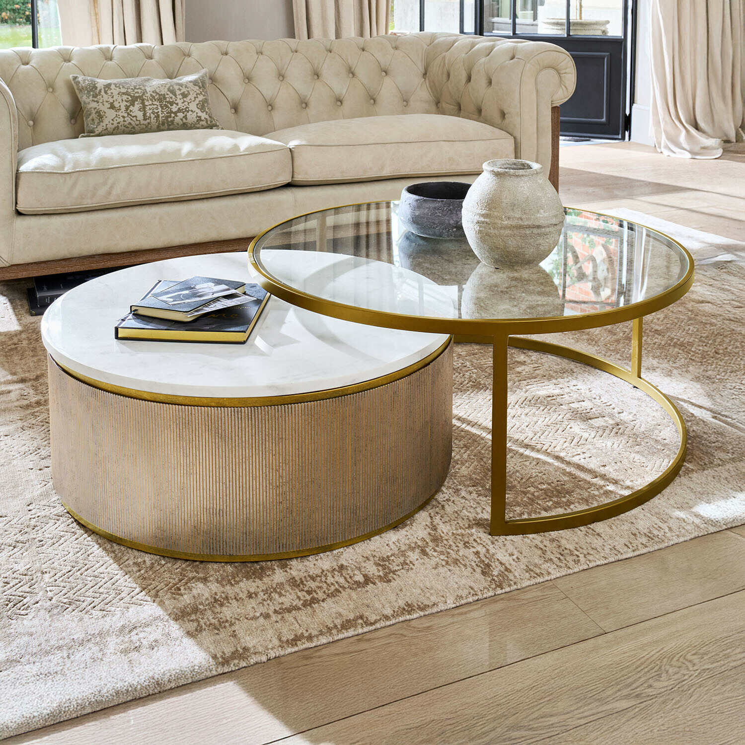 Ensemble de deux tables basses avec plateau en marbre et verre, cadre doré dans un salon lumineux