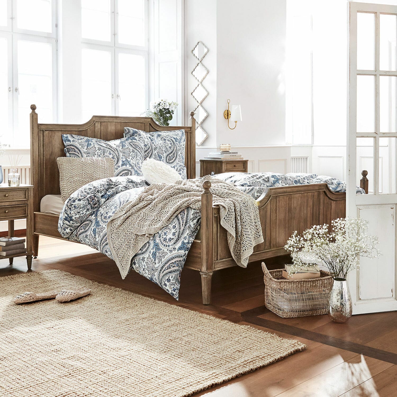 Chambre avec lit en bois et linge de lit bleu-blanc à motif paisley, tapis naturel et décorations