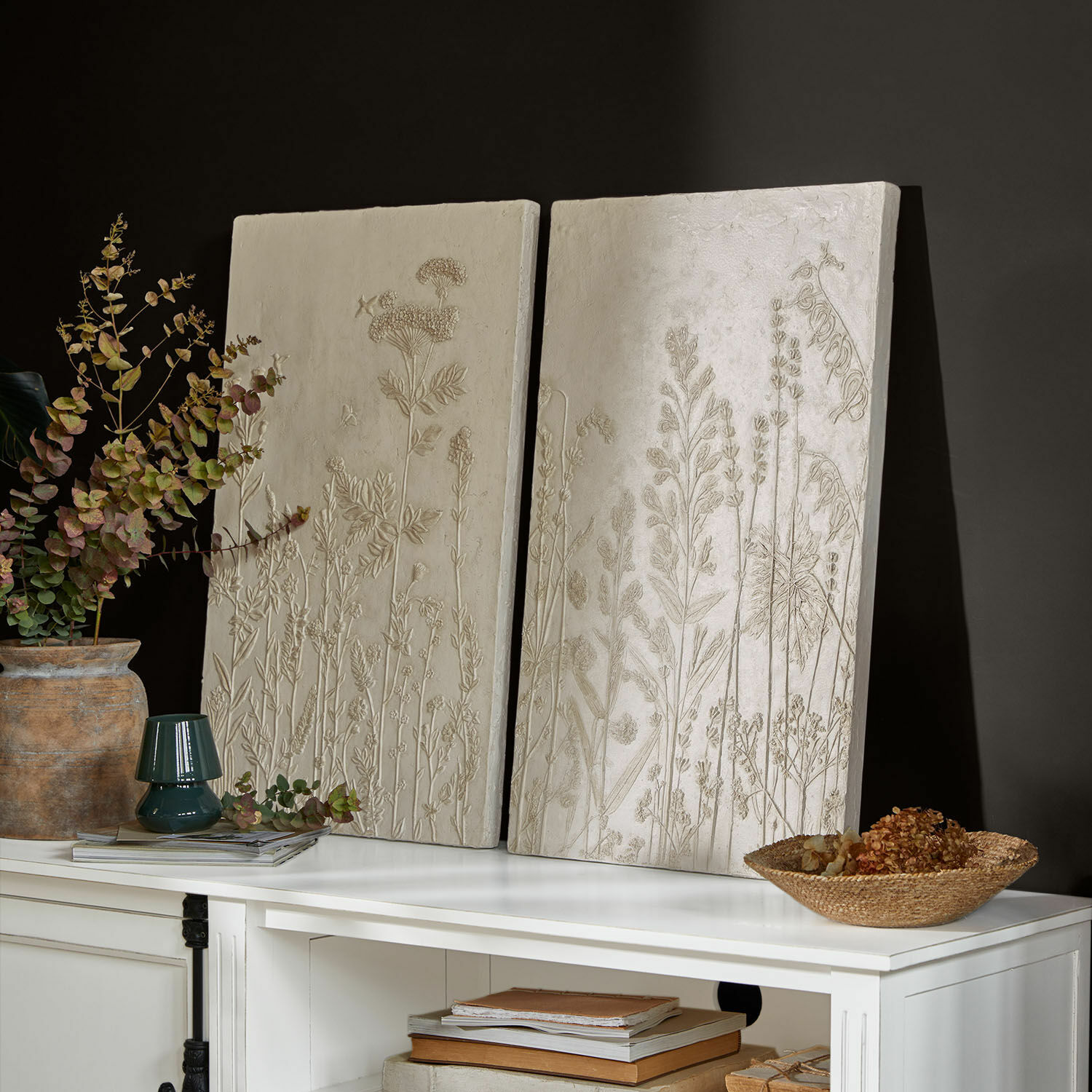 Lot de 2 tableaux Almahara Panneaux décoratifs crème avec reliefs floraux posés sur un meuble blanc moderne