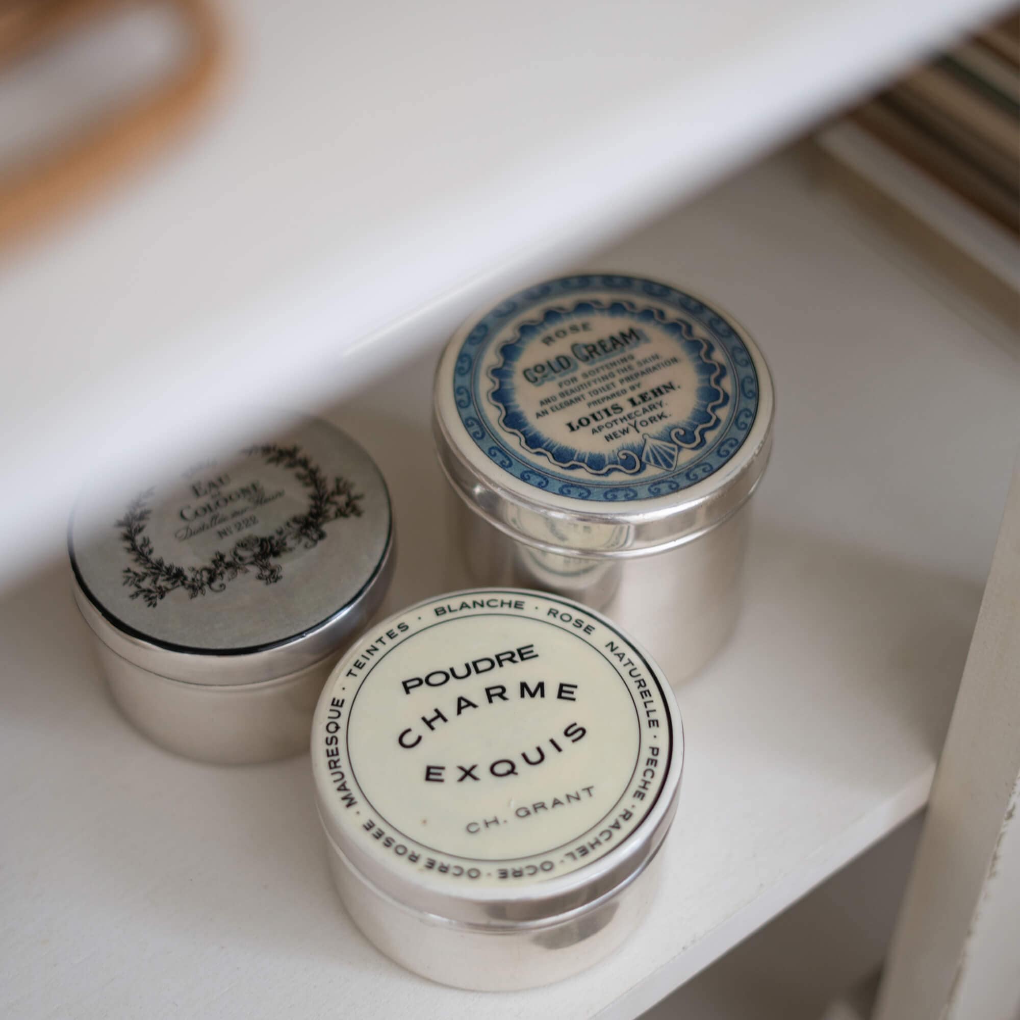 Trois boîtes métalliques vintage pour cosmétiques sur une étagère blanche pour rangement