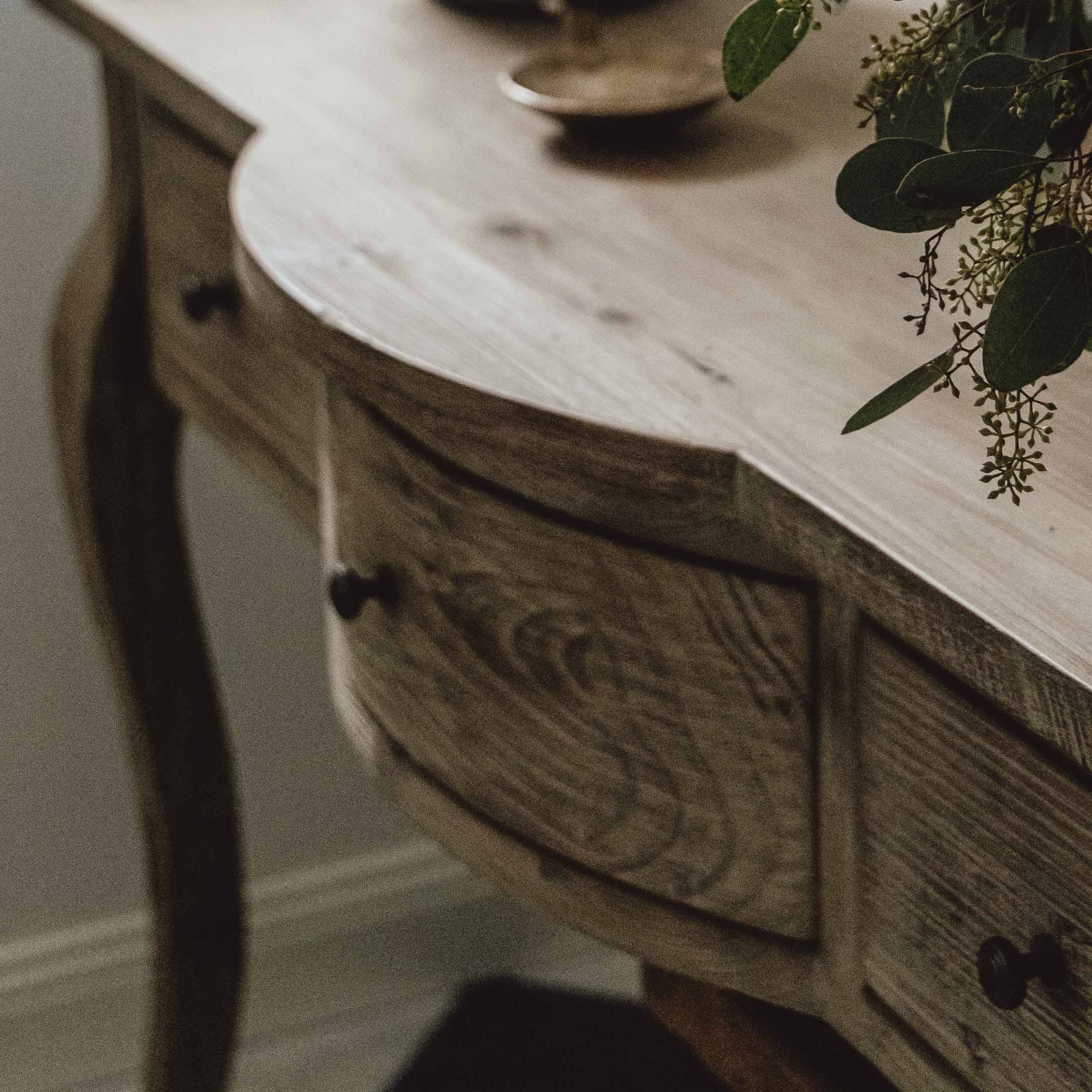 Table en bois naturel avec tiroirs et décoration végétale sur le dessus, meuble de salon élégant