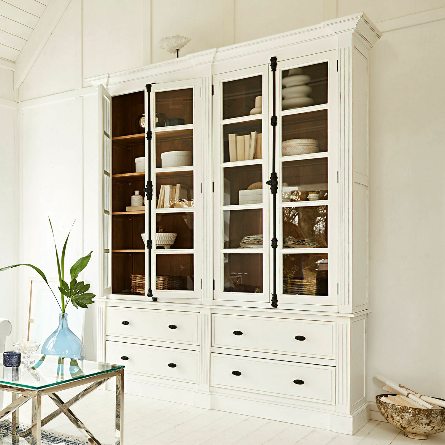 Bibliothèque Laimont Vitrine en bois blanc avec portes vitrées et poignées noires dans un intérieur lumineux