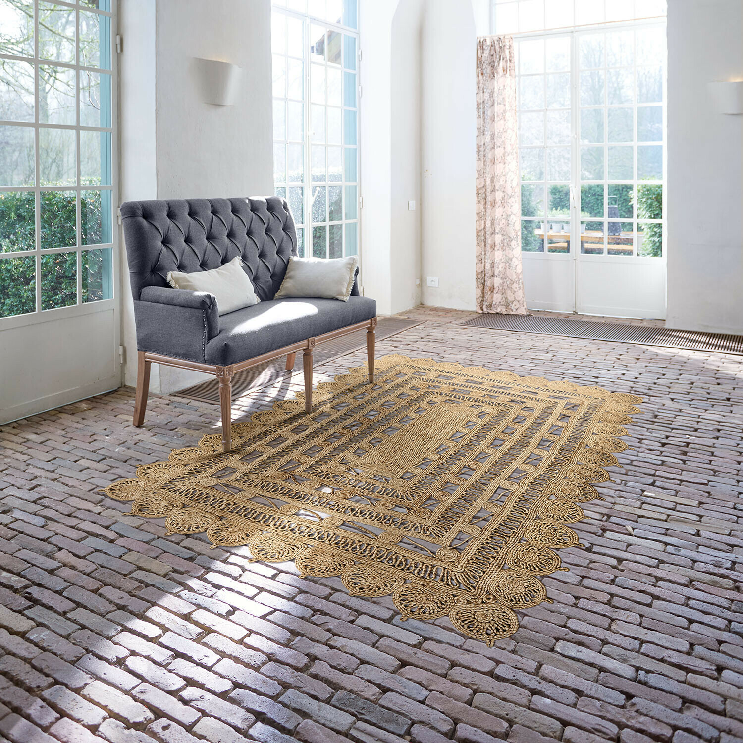 Tapis Livadia Canapé gris capitonné avec pieds en bois dans une pièce lumineuse avec tapis en jute sur sol en briques