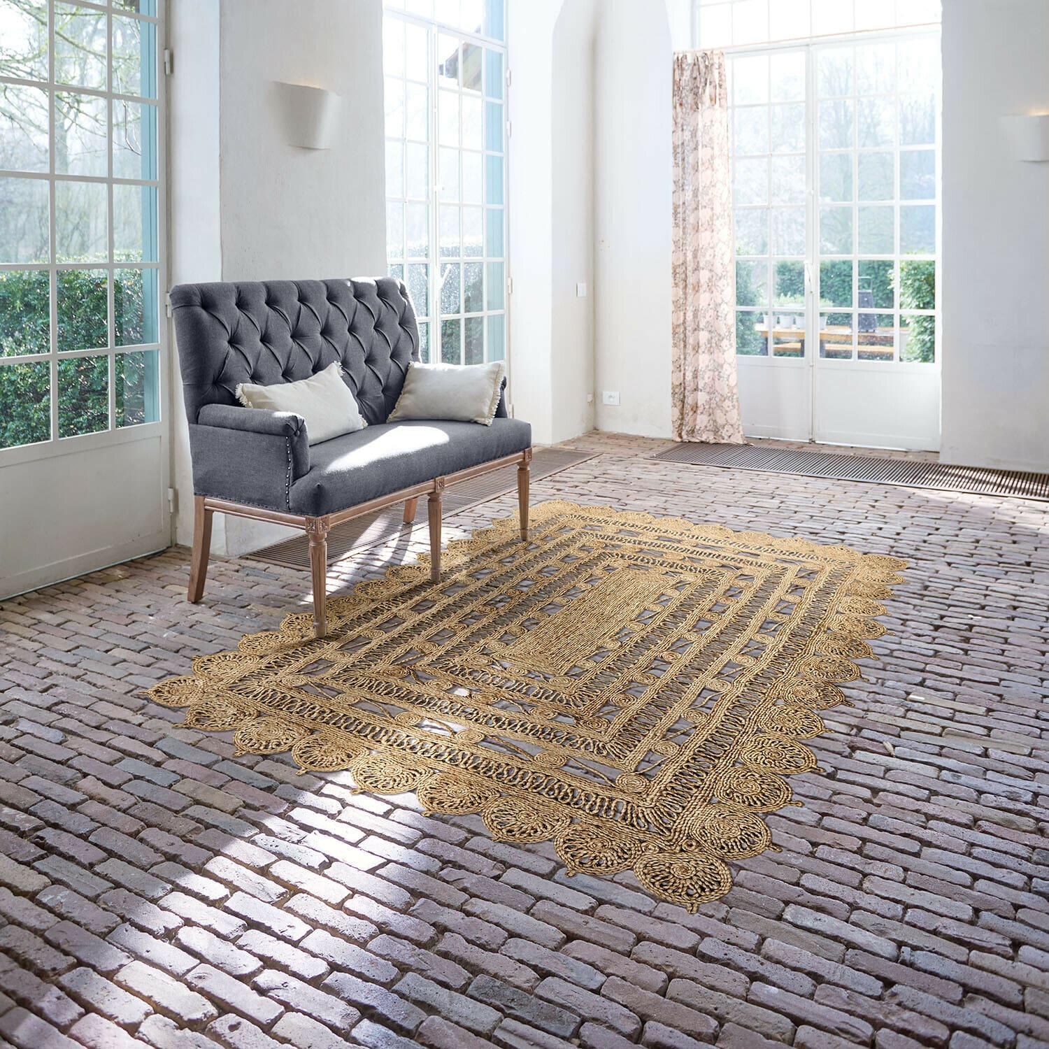Tapis Livadia Canapé gris capitonné avec pieds en bois dans une pièce lumineuse avec tapis en jute sur sol en briques